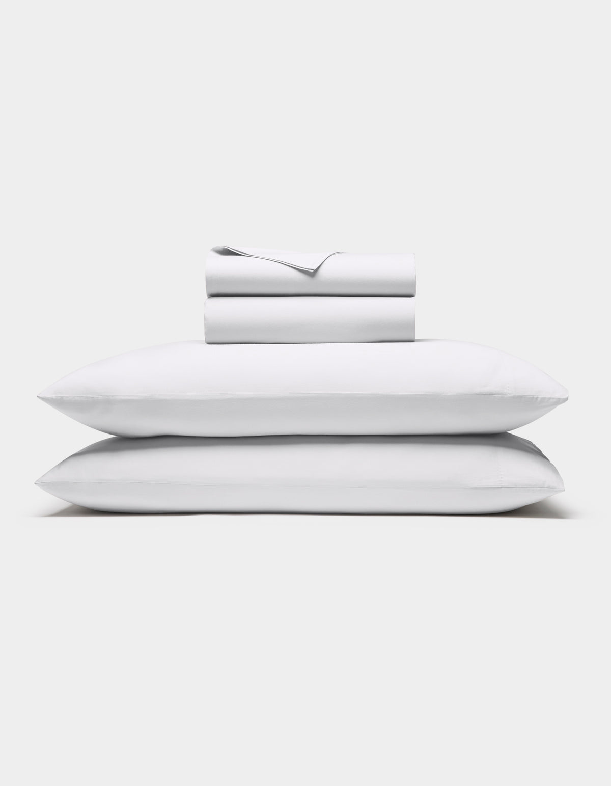 The Cozy Earth Soft-Wash Cotton Sheet Set in white, featuring a flat sheet, fitted sheet, and two pillowcases, is shown neatly stacked against a plain white background.