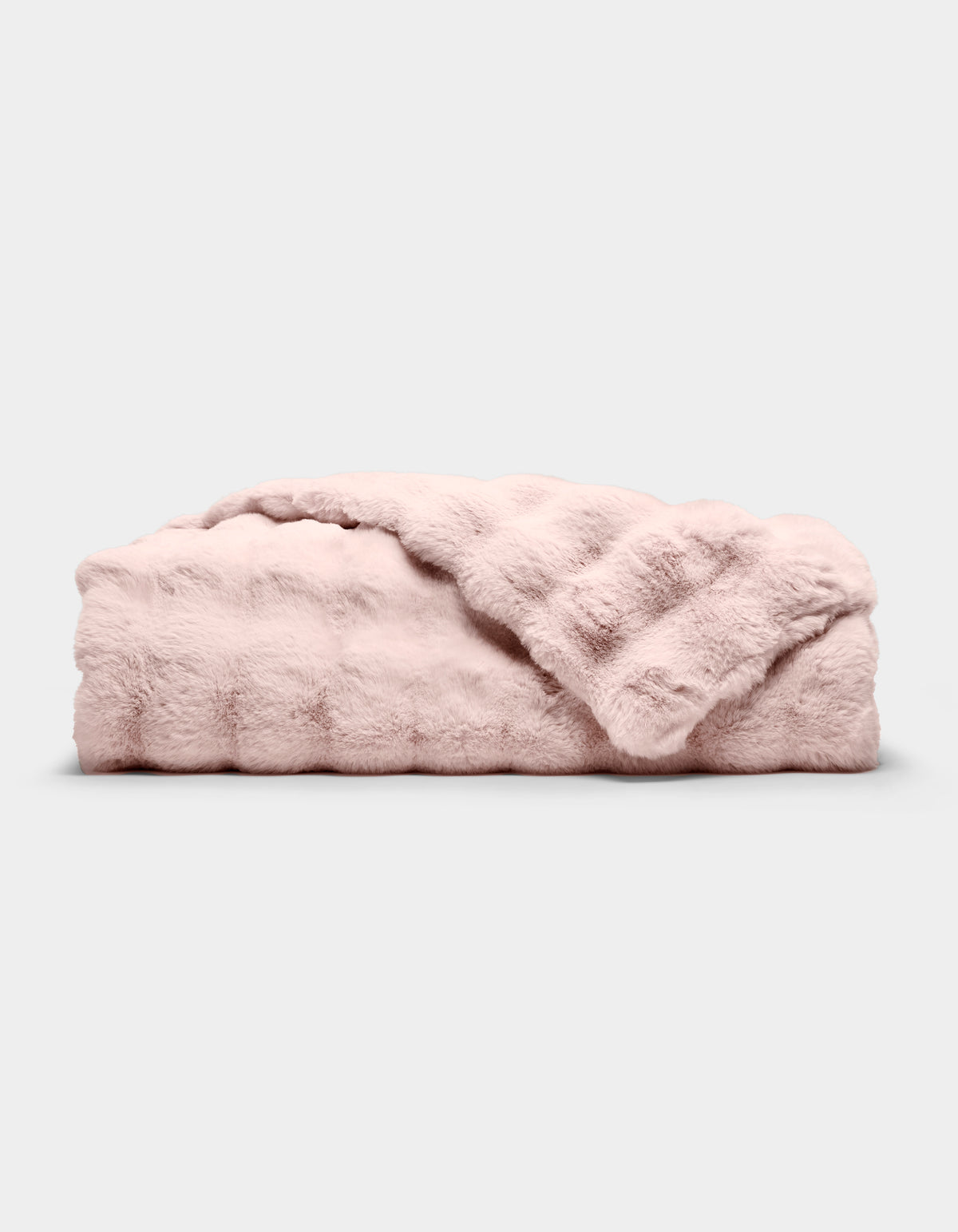 The Bubble Cuddle Blanket by Cozy Earth, in pale pink faux fur, is shown folded on a light gray background with one corner draped to reveal its soft texture.|Color:Blossom