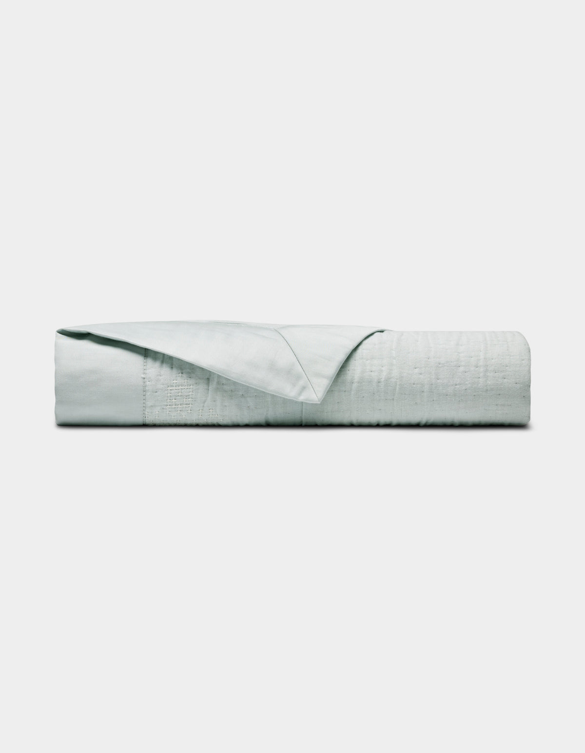 The Little Bee Matelasse Baby Blanket by Cozy Earth, shown neatly folded with one corner turned to reveal its smooth texture, is displayed in light gray or white against a plain white background.|Color:Vapor