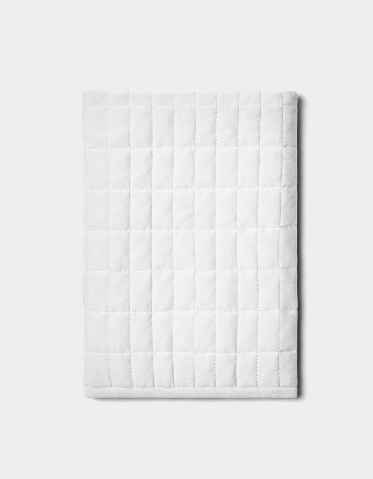 The Bamboo Jersey Quilted Shams by Cozy Earth are neatly folded with a square pattern and displayed on a plain light gray background.