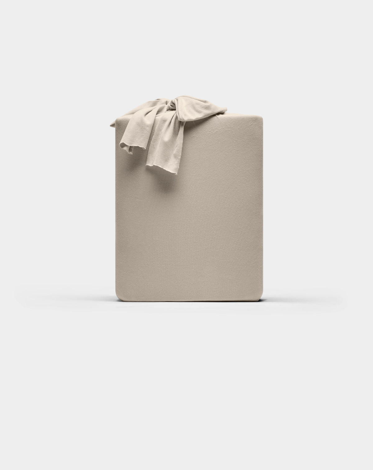 A neatly folded Cozy Earth Bamboo Jersey Sheet Set in beige, with a matching sheet draped over one corner, displayed against a plain white background.