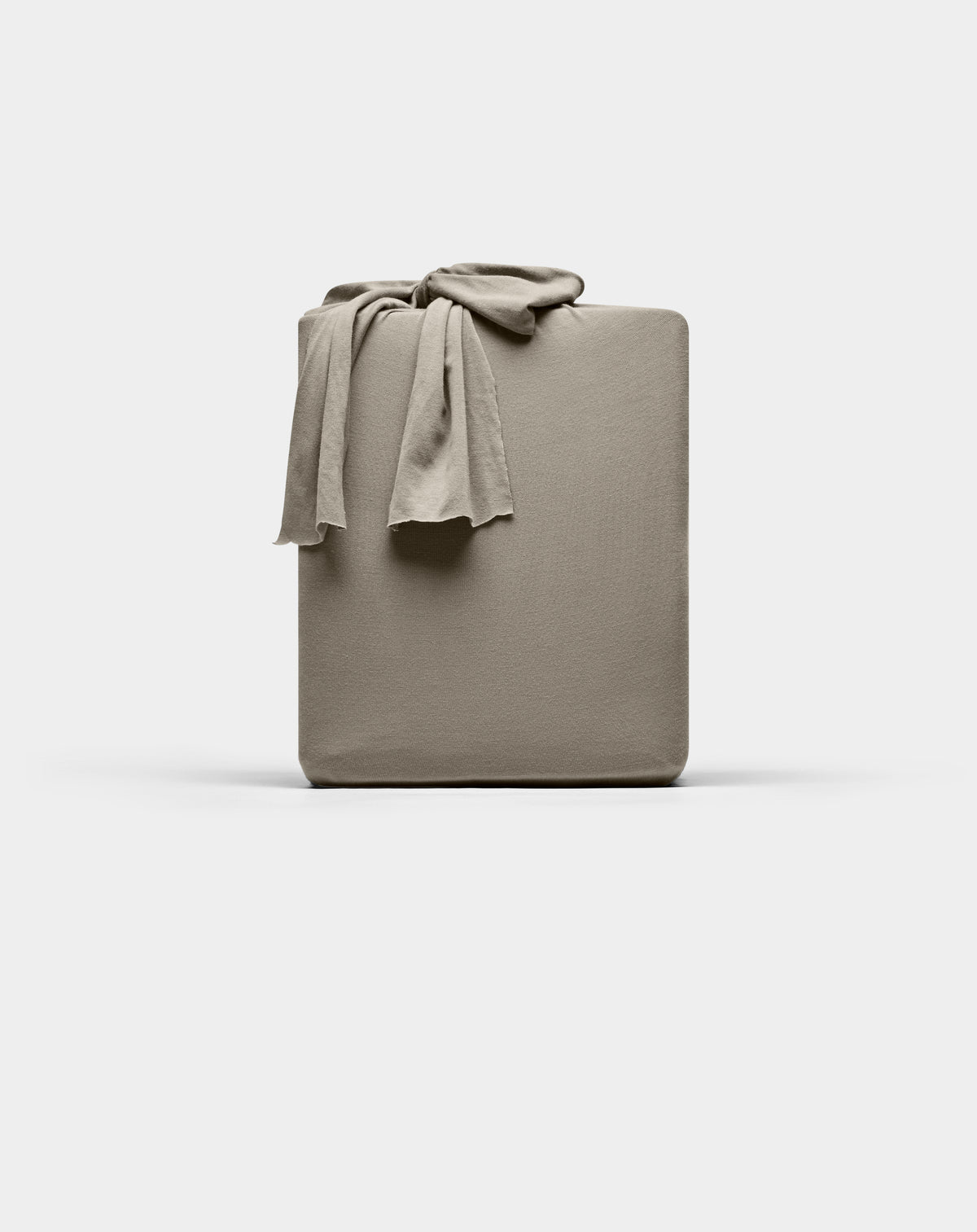 A taupe Cozy Earth Bamboo Jersey fitted sheet is neatly folded with one corner draped over the top, displayed against a plain white background.