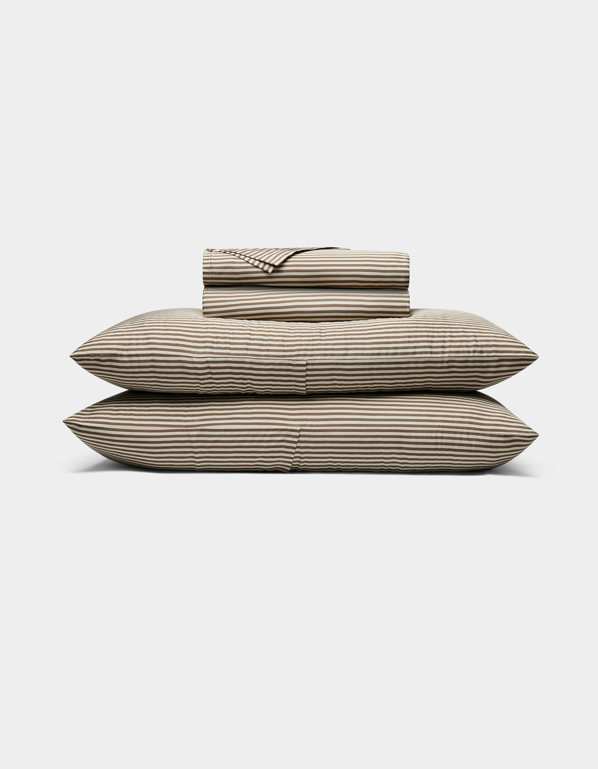 The Cozy Earth Bamboo Sheet Set, featuring striped beige and black sheets and pillowcases, is neatly stacked on two large pillows against a plain white background.