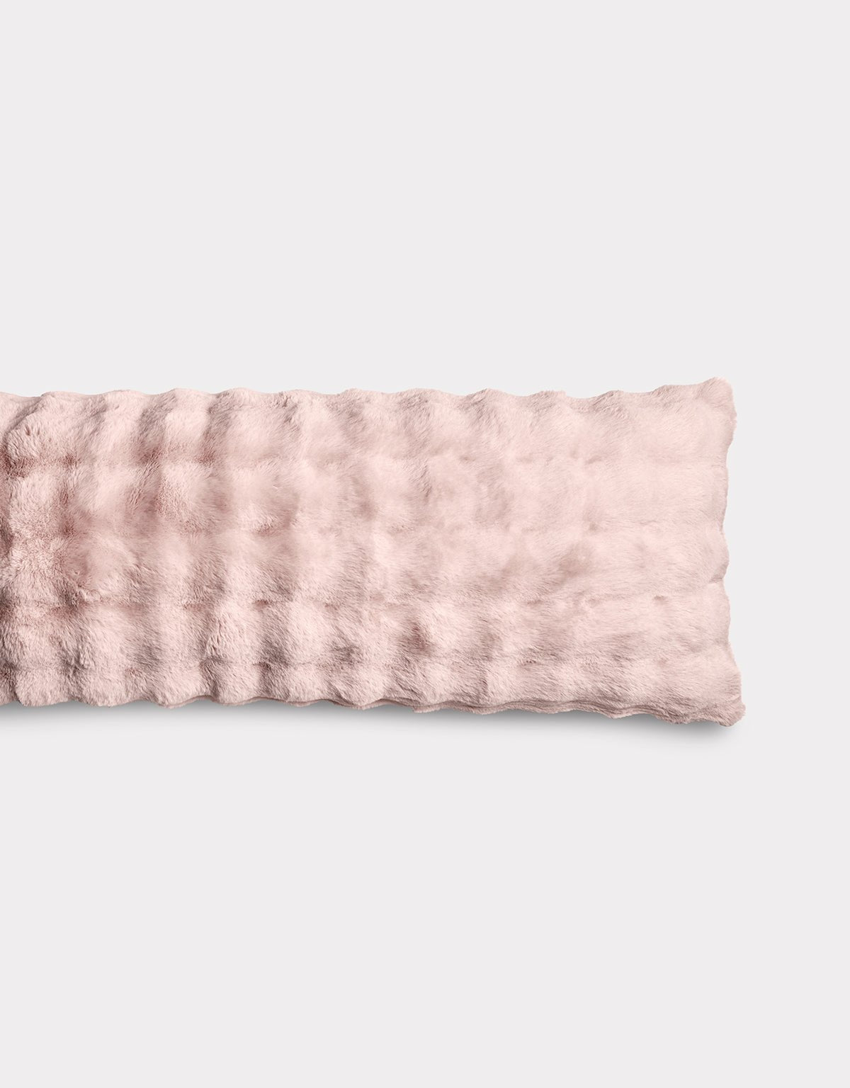 The Bubble Cuddle Pillow by Cozy Earth is a soft, light pink rectangular pillow with a plush, wavy-textured surface, displayed against a plain light background.|Color:Blossom |Size:Body - 20" x 54"