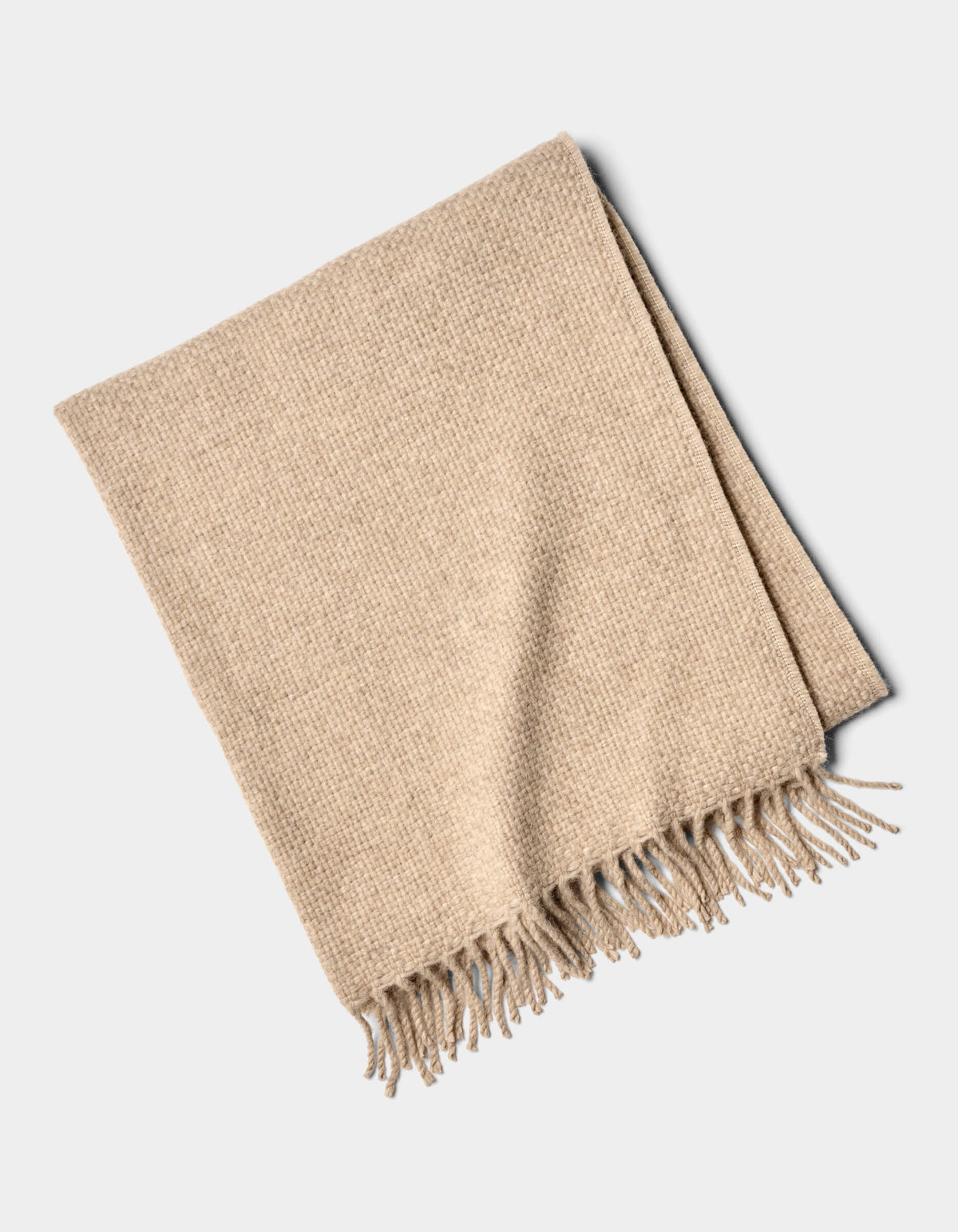 The Cozy Earth Lucia Throw is a neatly folded beige woven blanket with tasseled fringe on one edge, displayed on a plain white background.