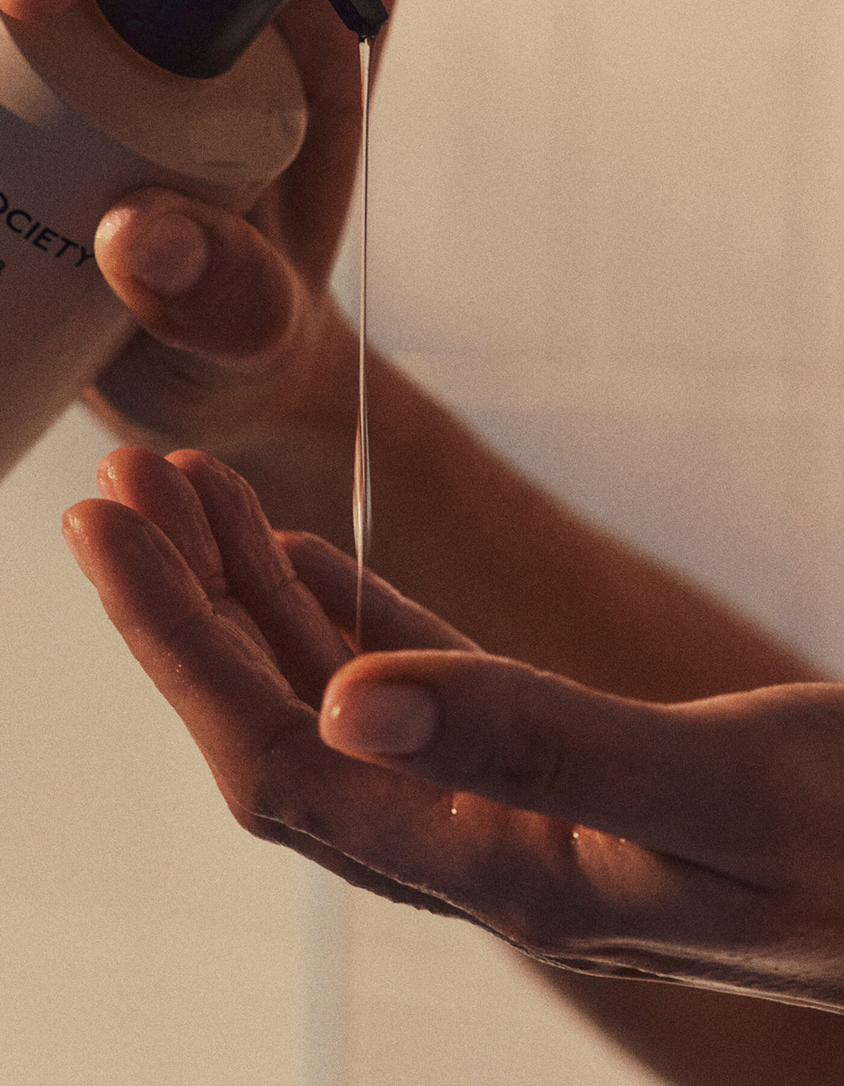 A close-up of hands pouring Cozy Earth's Fount Society Intro Kit into their palm, softly illuminated by warm light.