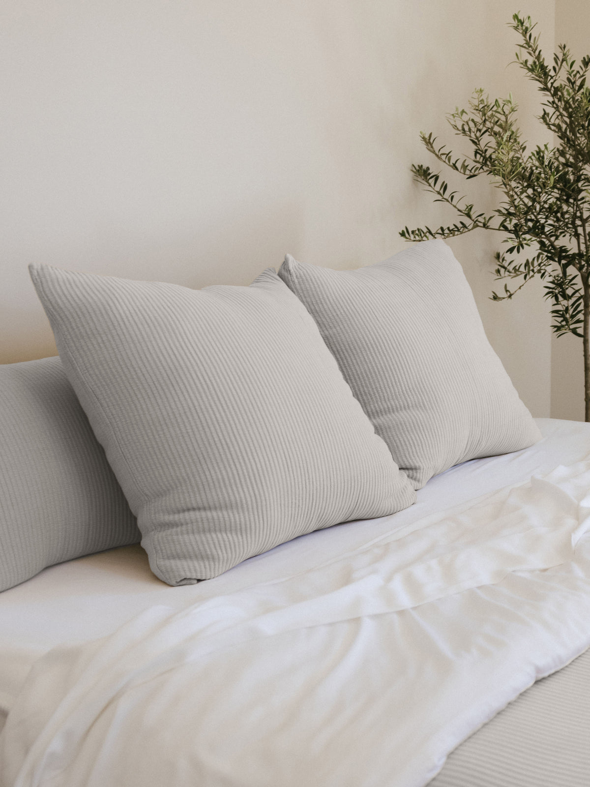 Light Grey coverlet shams on white bed 