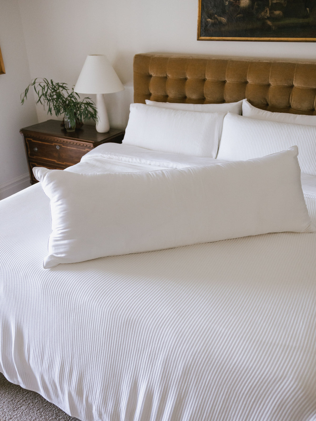 Body pillow laying on the middle of white bed 