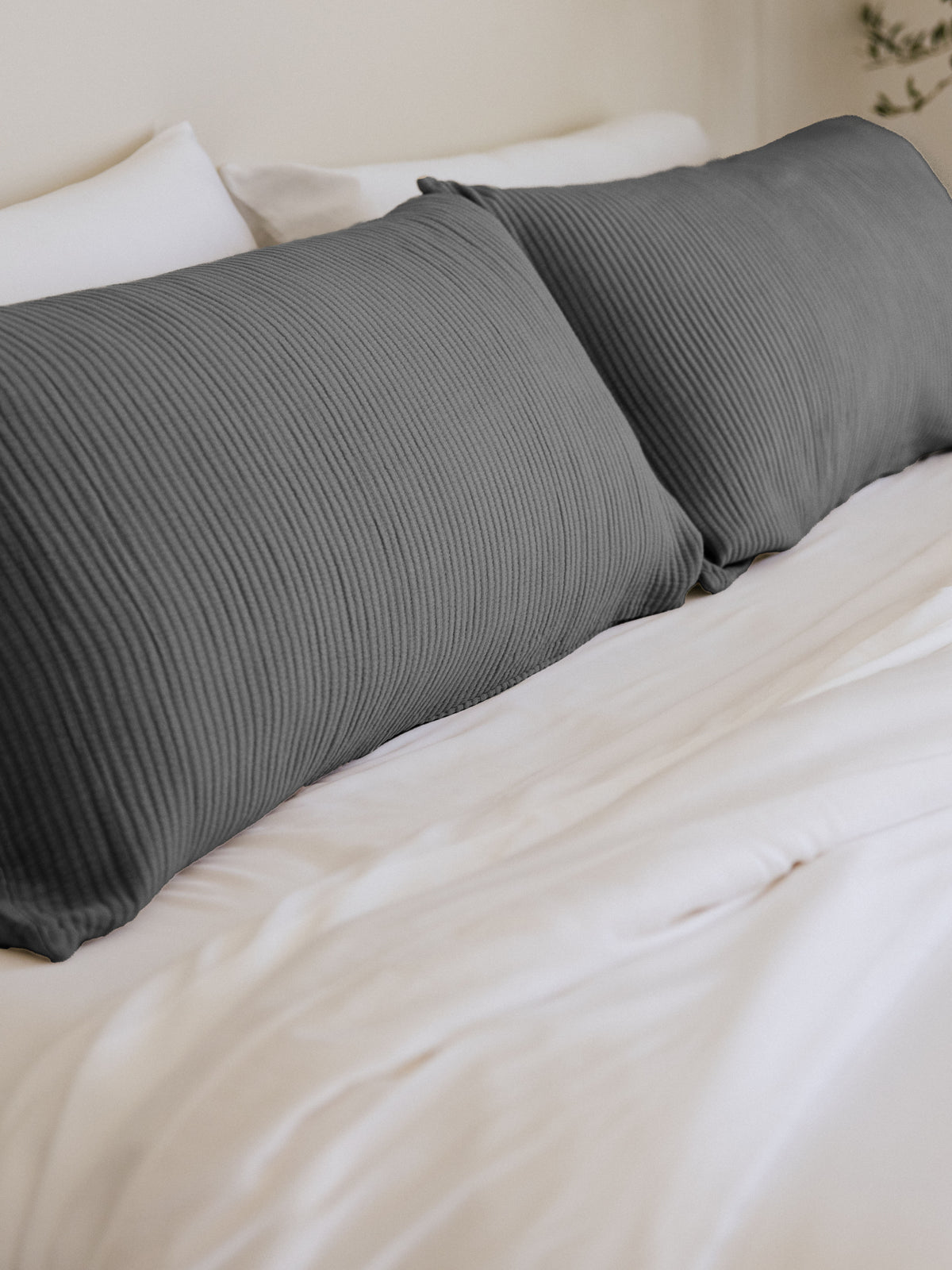 Charcoal coverlet shams on white bed 