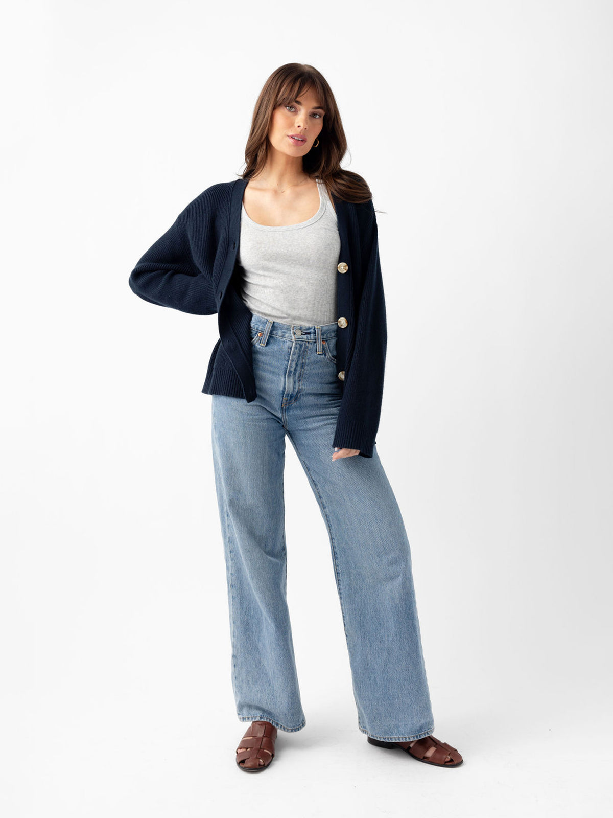 Woman standing with white background wearing jeans and eclipse cardigan 