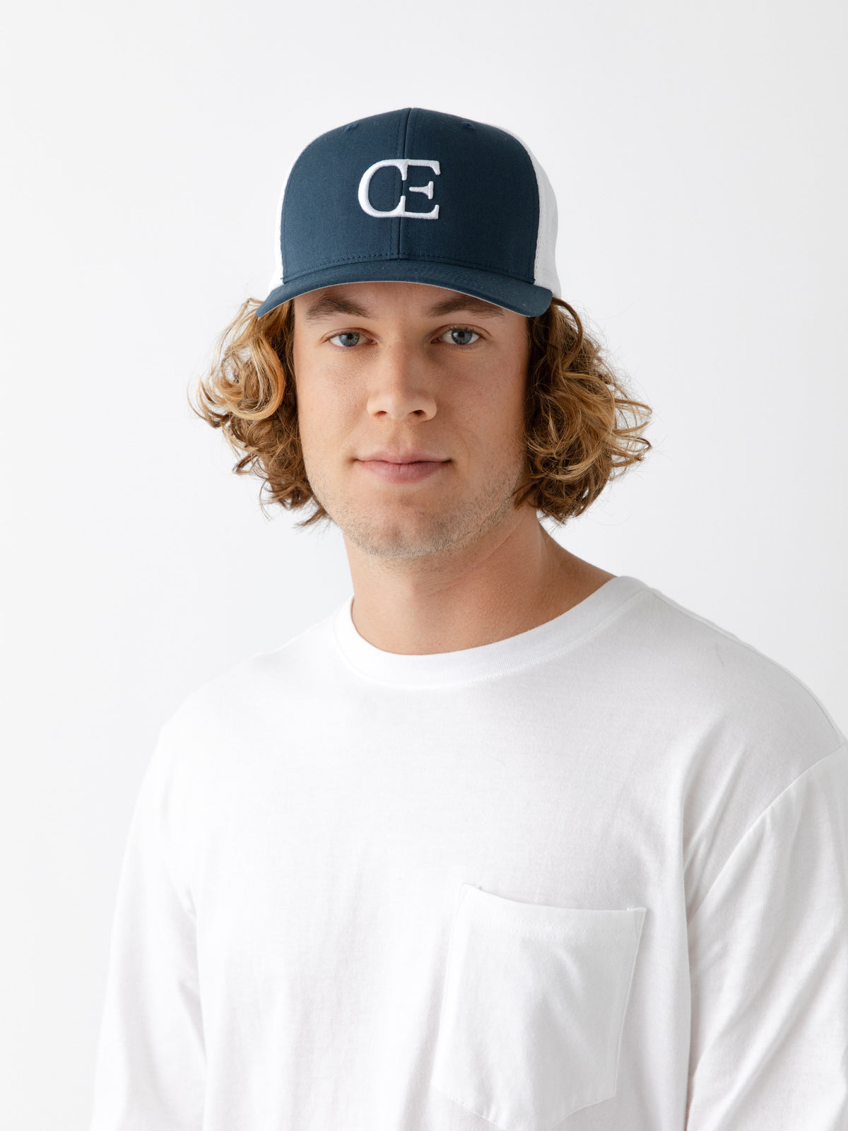 Man wearing a Navy and white cap with a CE logo on a light gray background 