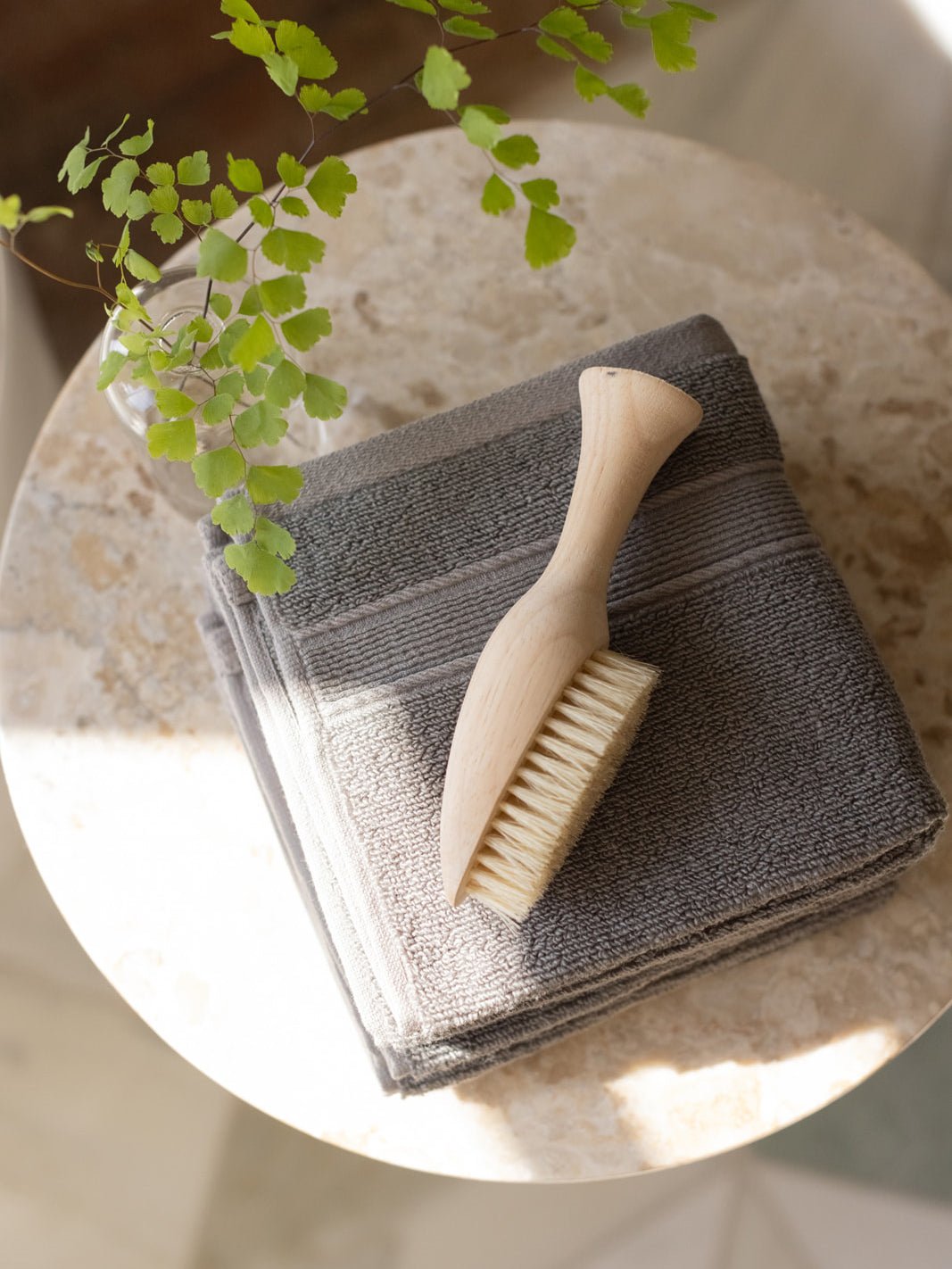 Charcoal washcloths folded on small table with brush 
