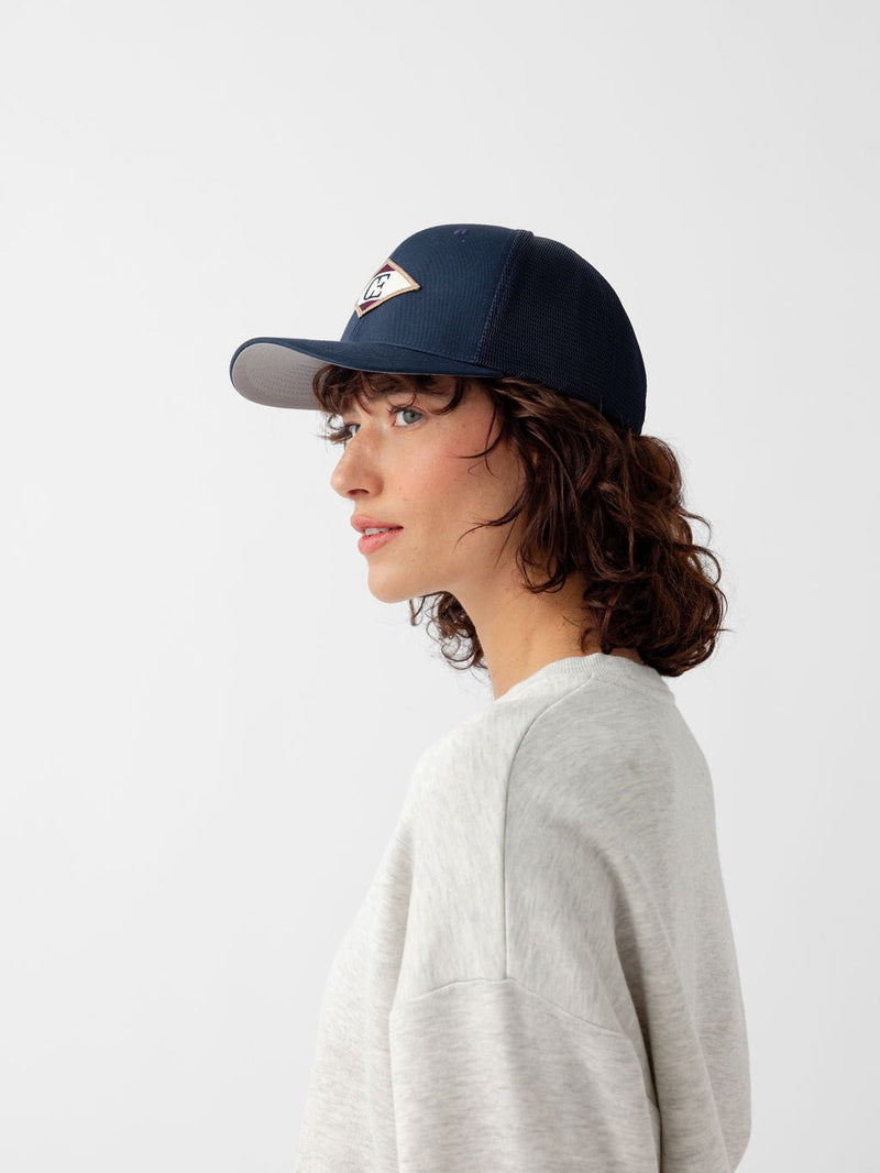 Side view of woman wearing navy diamond mesh trucker hat