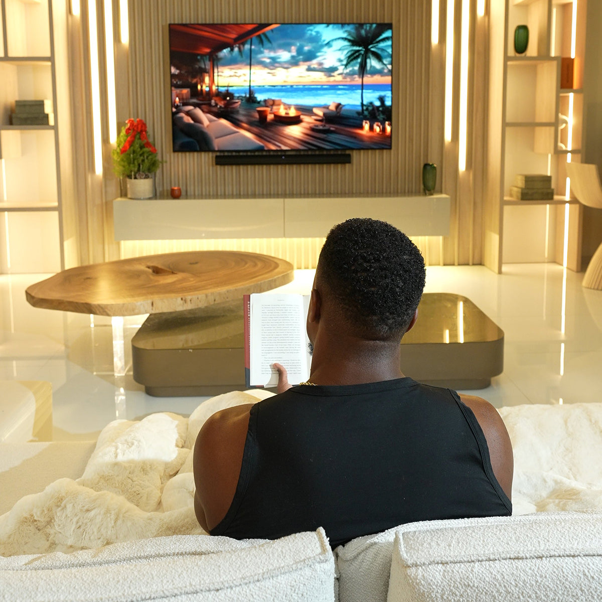Ashton Hall sitting on a couch watching television in a modern living room.