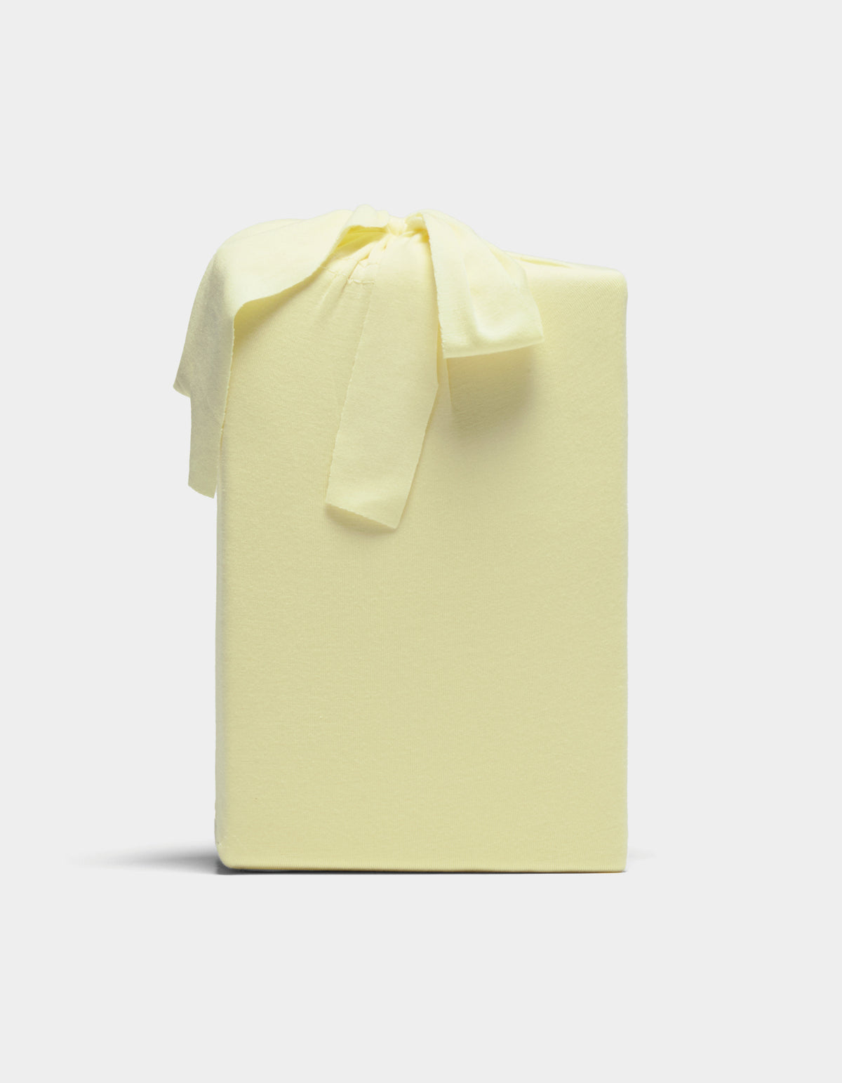 A Cozy Earth Bamboo Jersey Sheet Set, neatly wrapped in pale yellow fabric with a matching bow, is displayed against a plain light background.
