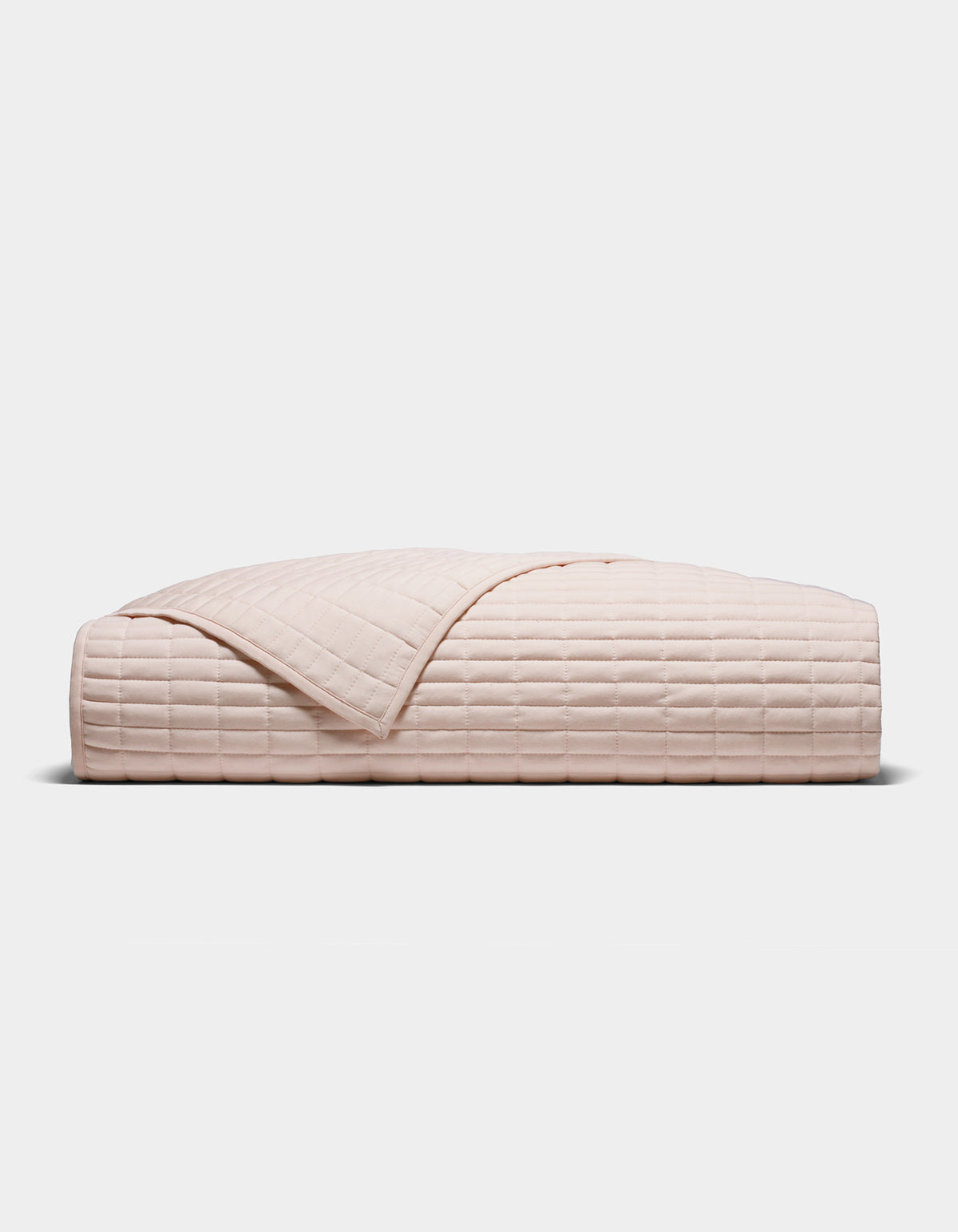 The Cozy Earth Bamboo Jersey Quilt, shown folded in blush-pink with a quilted grid pattern, is displayed against a plain white background.