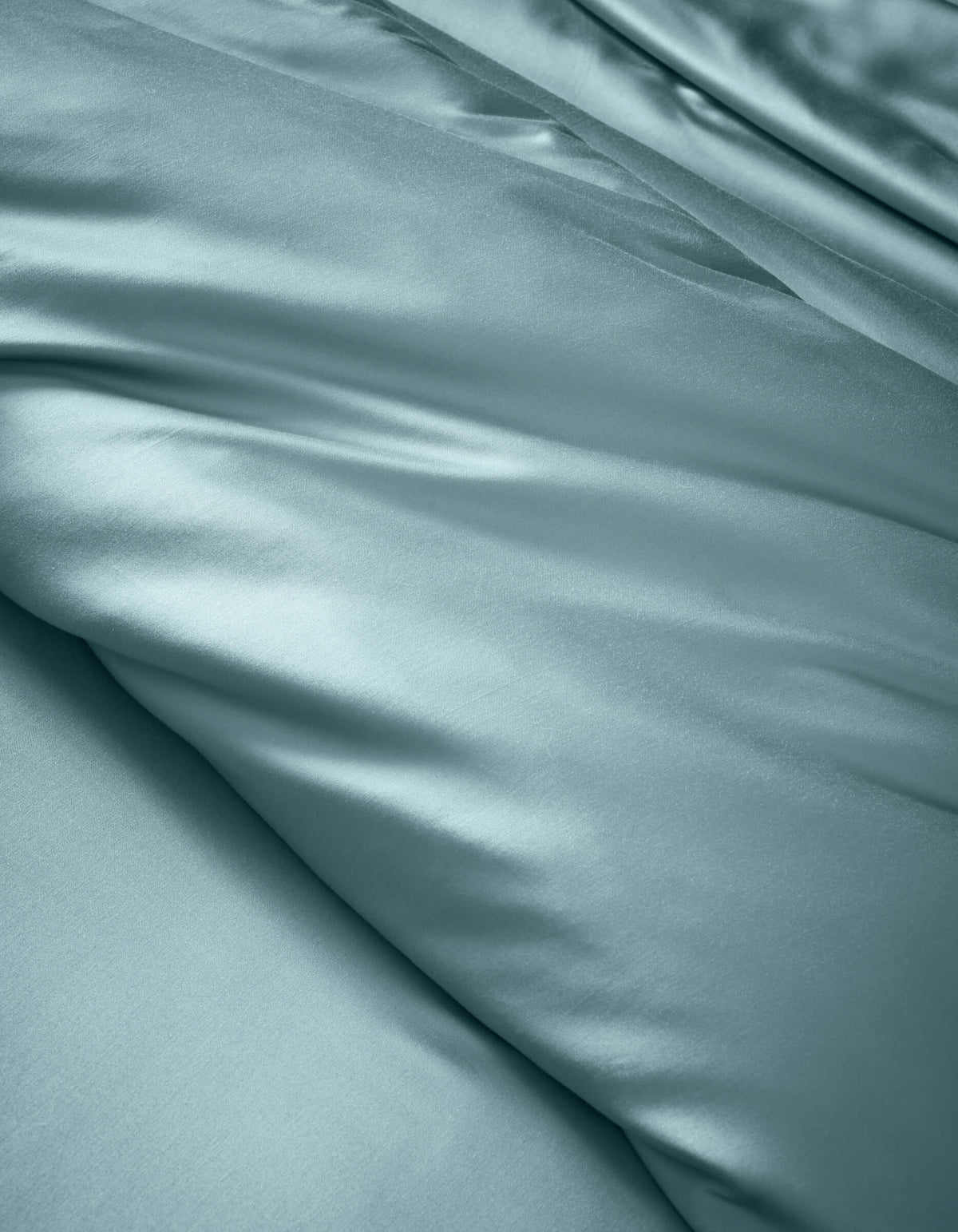 The Cozy Earth Bamboo Duvet Cover features smooth, light blue satin fabric with soft folds and a gentle sheen, offering a luxurious and elegant look.
