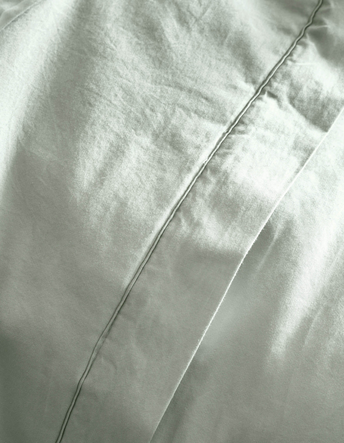 Close-up of Cozy Earth's Soft-Wash Cotton Quilt in light gray, highlighting the diagonal seam, soft folds, and textured fabric.