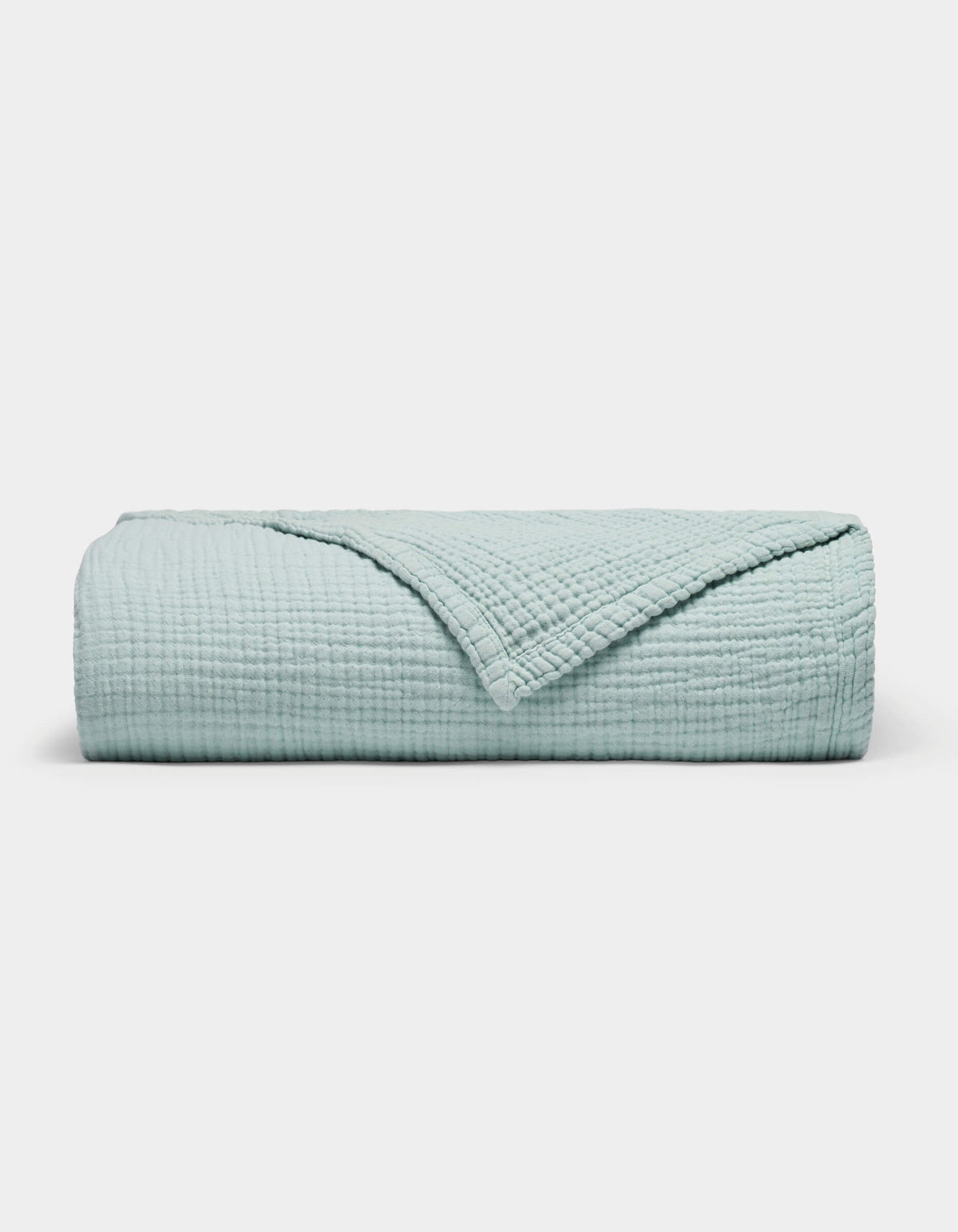 The Cozy Earth Cotton Gauze Blanket is neatly folded in light blue with a textured, grid-like pattern on a plain white background. One corner is turned down to reveal the inner side.