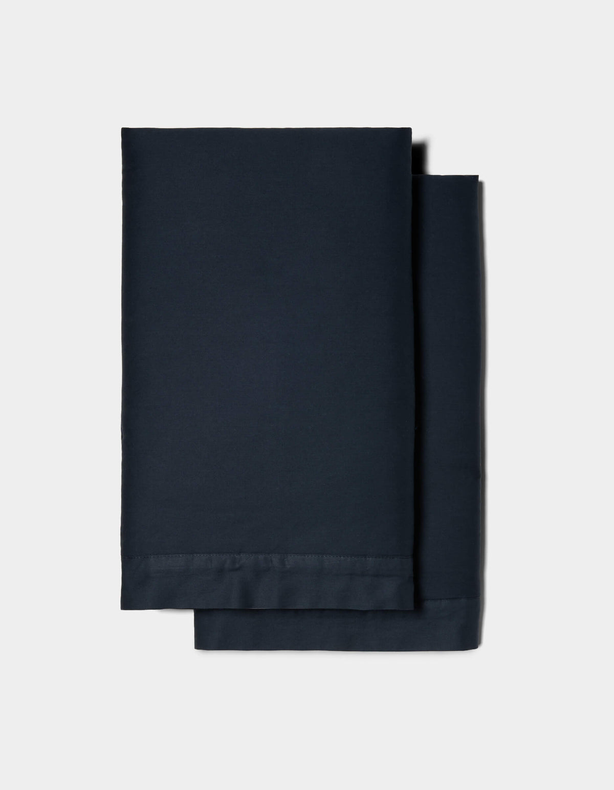 Two neatly folded Soft-Wash Cotton Shams by Cozy Earth, in dark navy blue, stacked together against a plain light gray background.