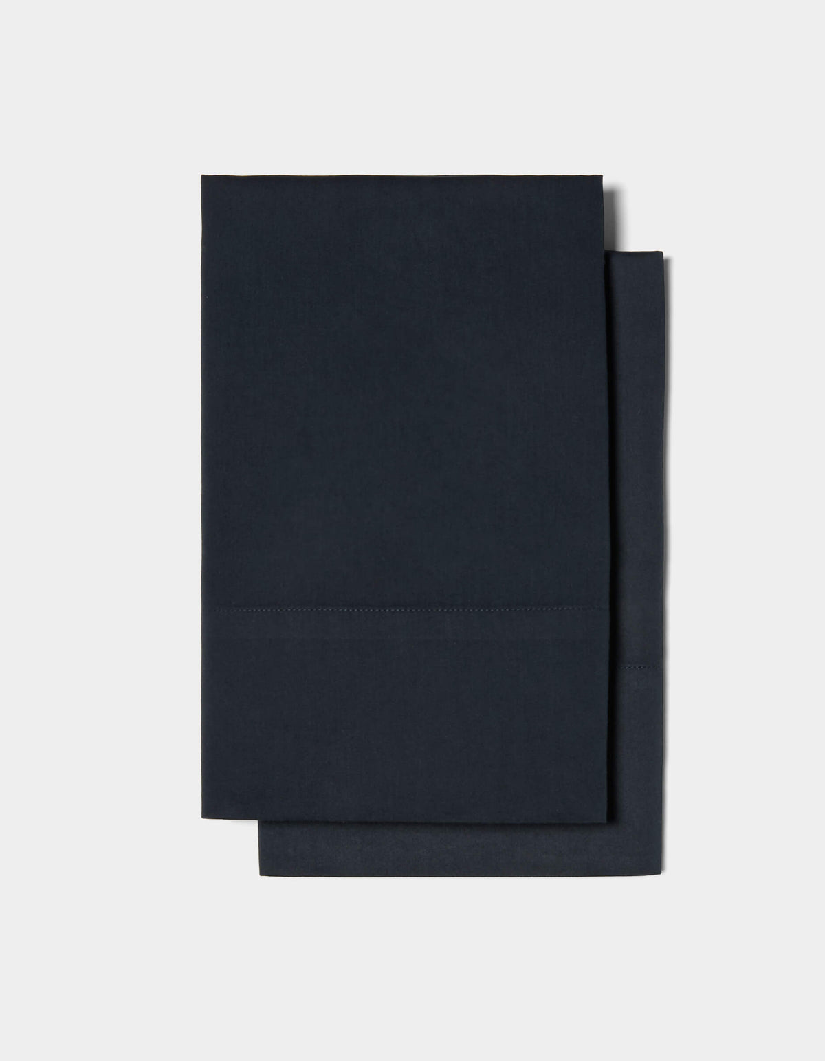Two neatly folded Soft-Wash Cotton Pillowcases by Cozy Earth are stacked on top of each other against a plain white background.
