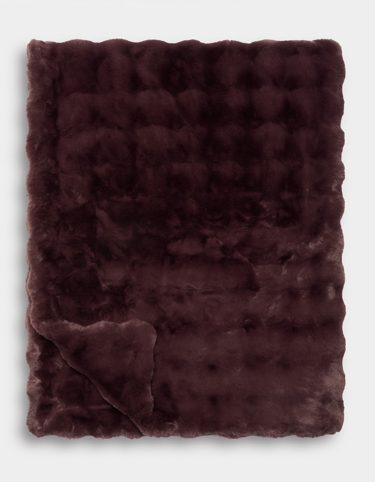 A Bubble Cuddle Blanket by Cozy Earth is displayed folded with one corner turned up, revealing its soft texture and subtle checkered pattern.|Color:Raisin