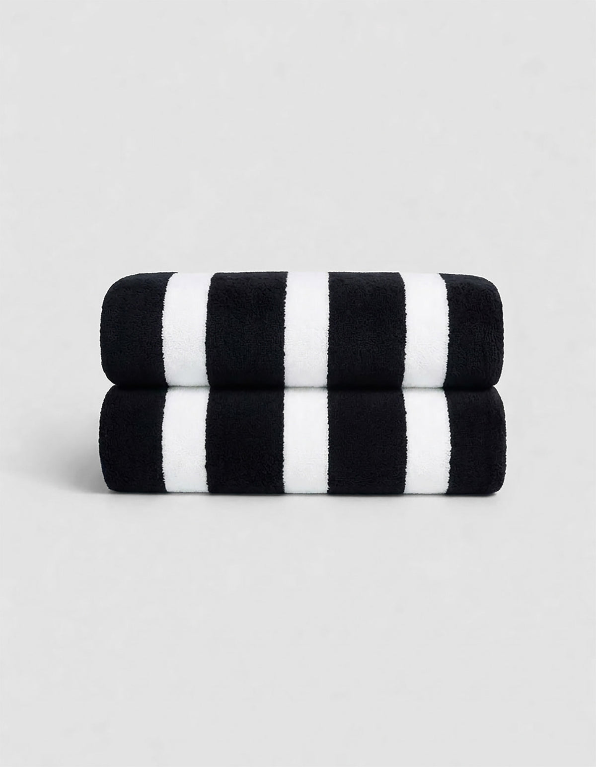 The Cozy Earth Classic Stripe Resort Towel Bundle features two neatly stacked towels with thick black and white stripes, set against a plain light gray background.