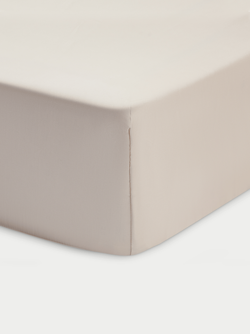 A close-up of the Cozy Earth Bamboo Fitted Sheet in beige, showing smooth fabric and a stitched seam running vertically down the tightly covered mattress corner.