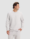 A man wears the Cozy Earth Men's Dylan Crewneck with matching sweatpants, smiling and looking to the side against a plain light background.|Color:Dew
