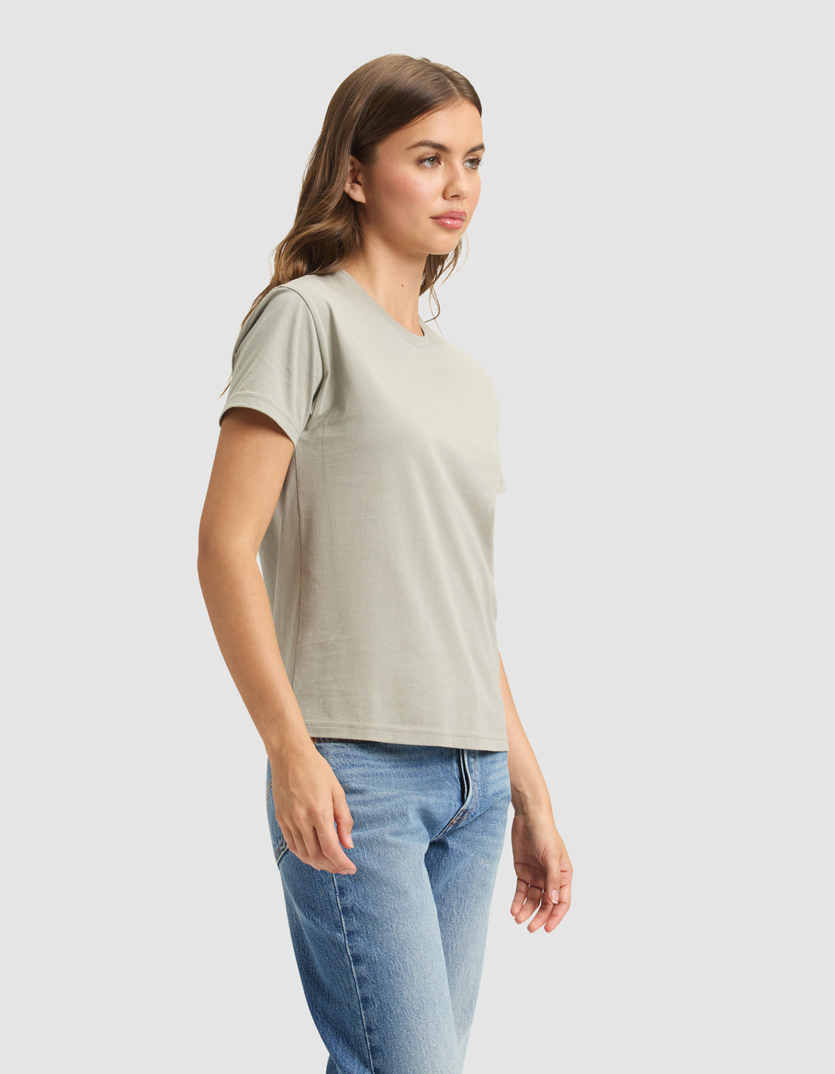 A woman models the Cozy Earth Women's Easy Tee in light gray with blue jeans, standing slightly sideways against a plain light background. |Color:Palm