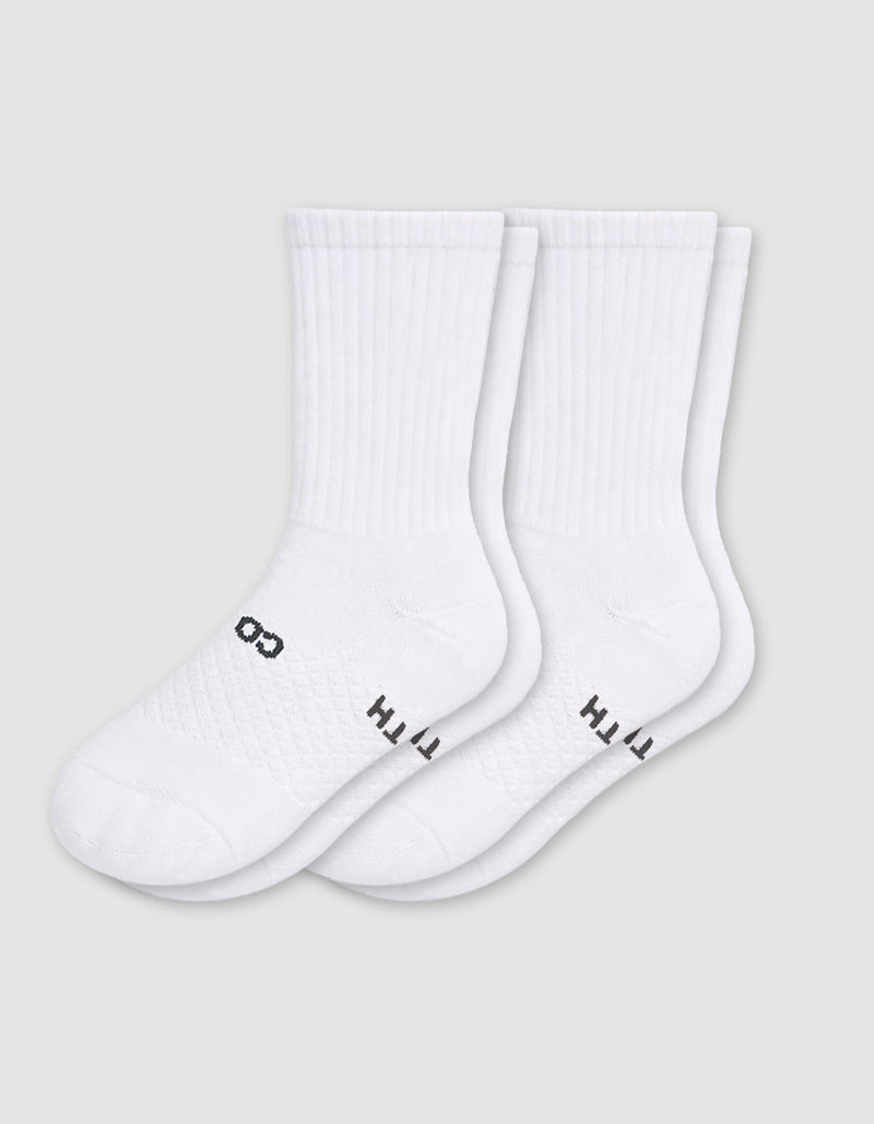 Two pairs of Cozy Earth Women's Essential Calf Socks in white, featuring ribbed cuffs and small black lettering on the soles, are laid side by side on a light gray background.