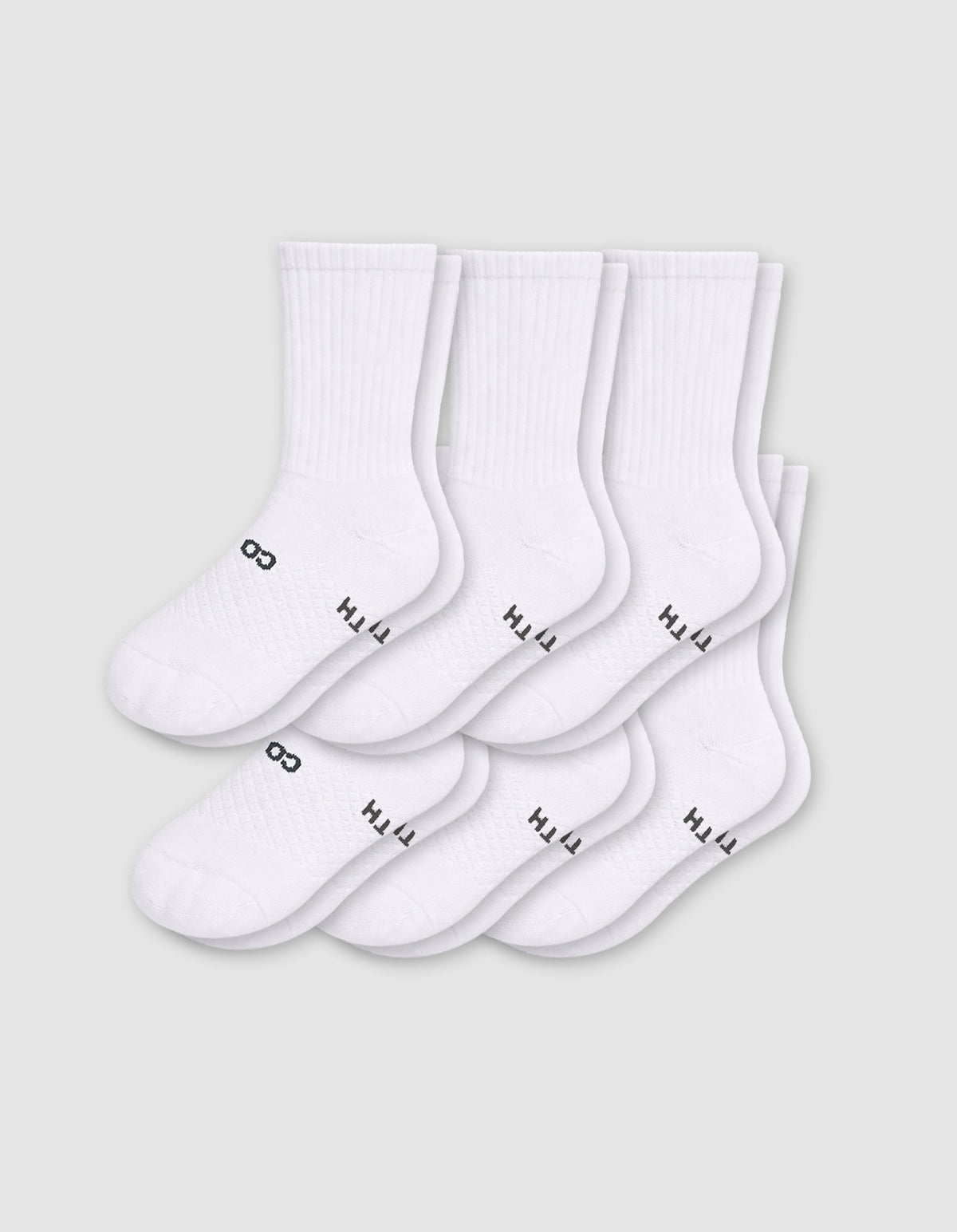 Six pairs of Cozy Earth Men's Essential Calf Socks in white are arranged in two rows on a light gray background, each featuring small black text and a symbol near the toes and ribbed cuffs.|Color:White
