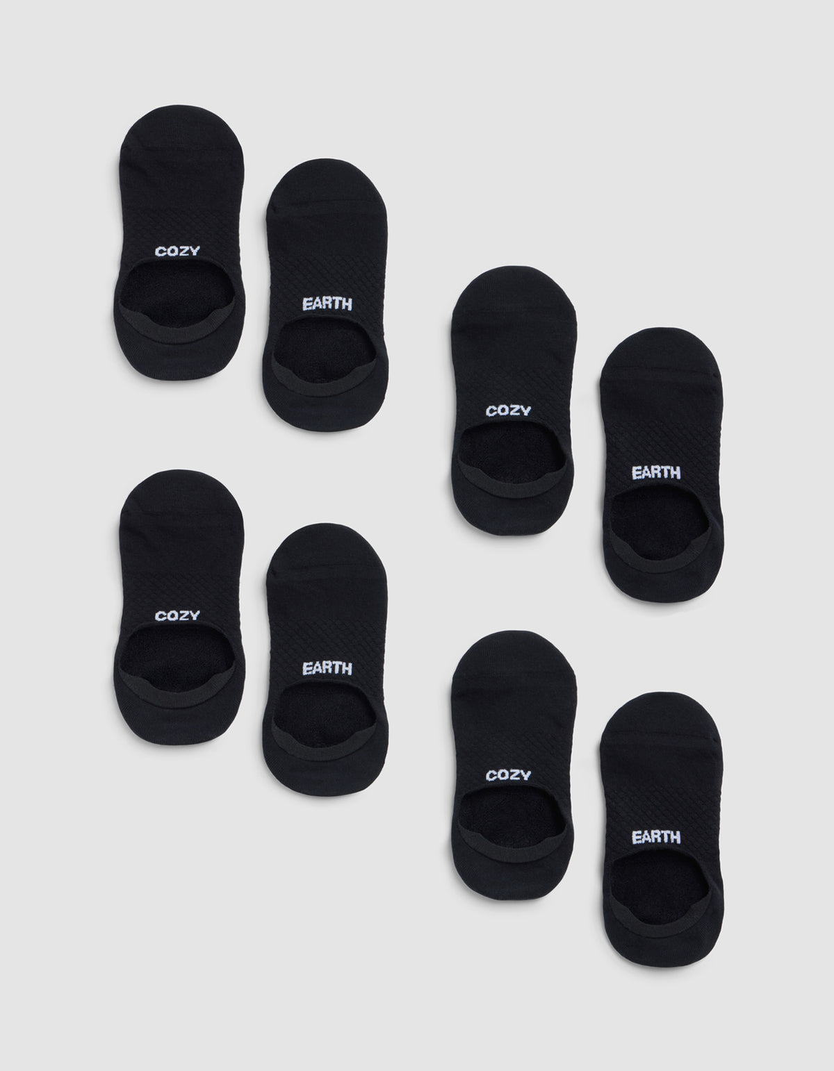 Eight pairs of black Essential No-Show Socks from Cozy Earth on a light gray background—four pairs read "COZY" and four read "EARTH" in white lettering on top. 