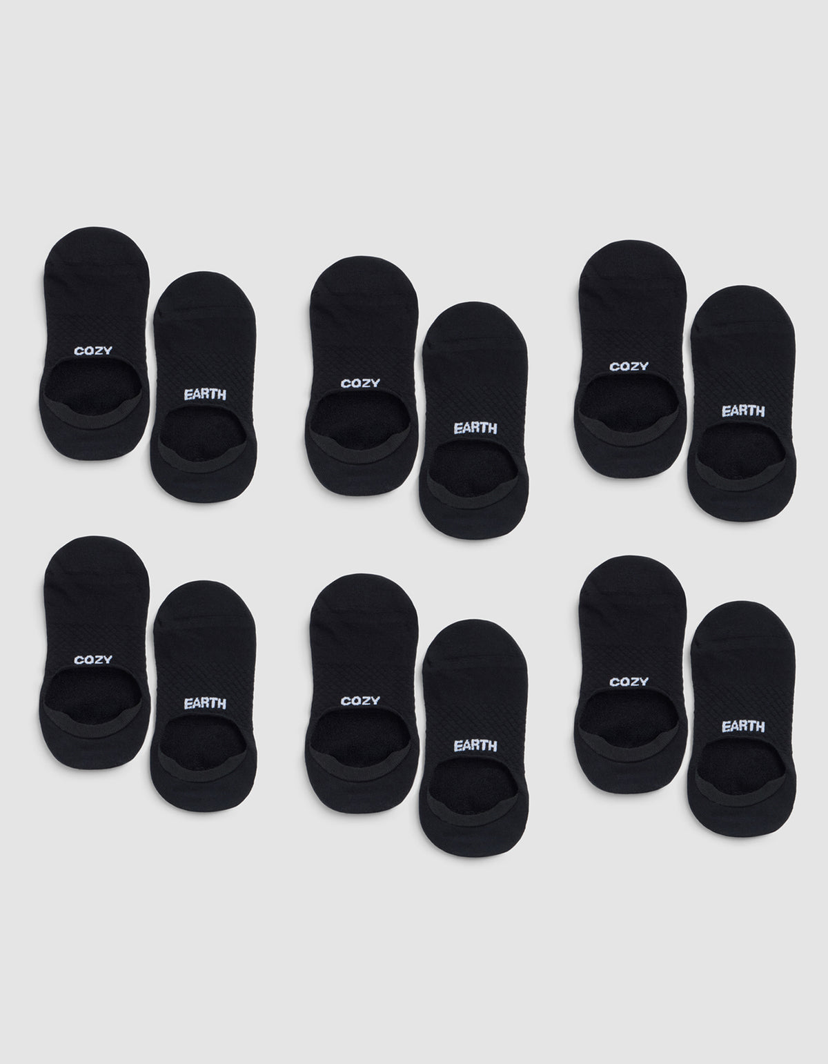 Six pairs of black Essential No-Show Socks by Cozy Earth are arranged in four rows on a light gray background, each labeled "COZY" or "EARTH" near the opening. 