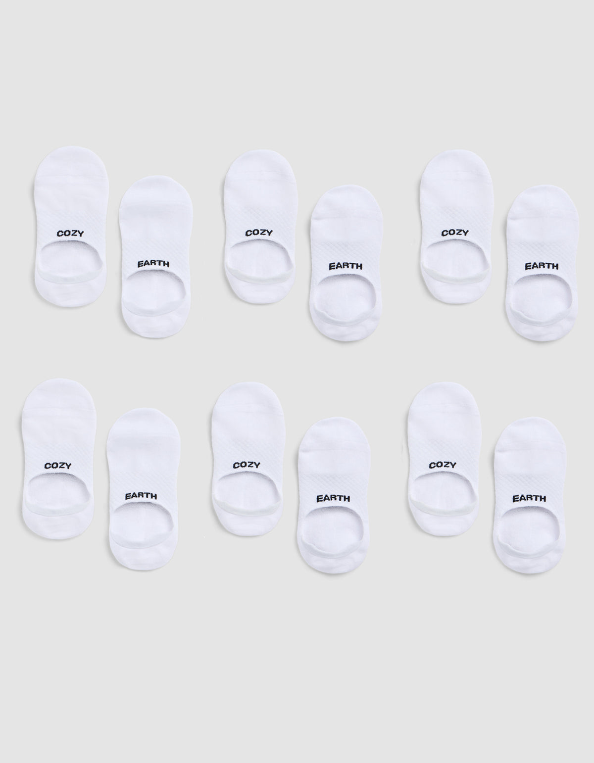 A 6-pack of white Essential No-Show Socks by Cozy Earth, each pair featuring "COZY" or "EARTH" in black text on top, displayed on a light gray background. 