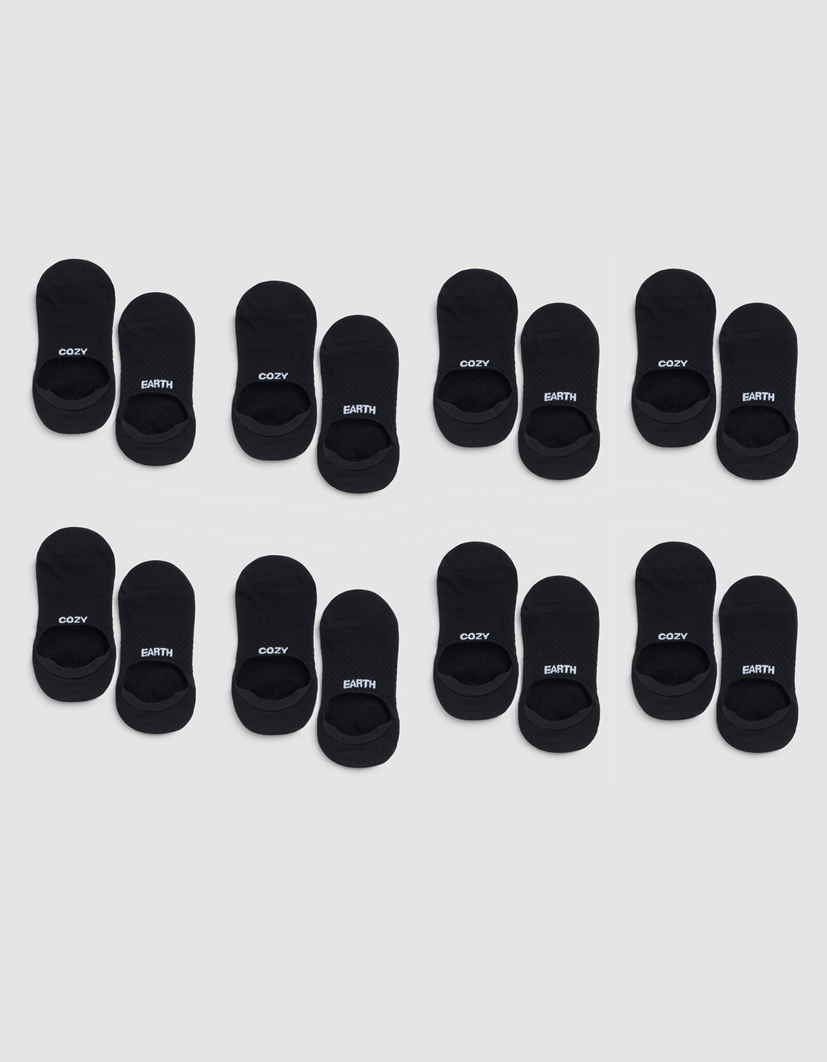 Eight pairs of Cozy Earth Essential No-Show Socks are arranged in three rows on a light gray background, with "COZY" and "EARTH" printed in white letters on the black socks. 