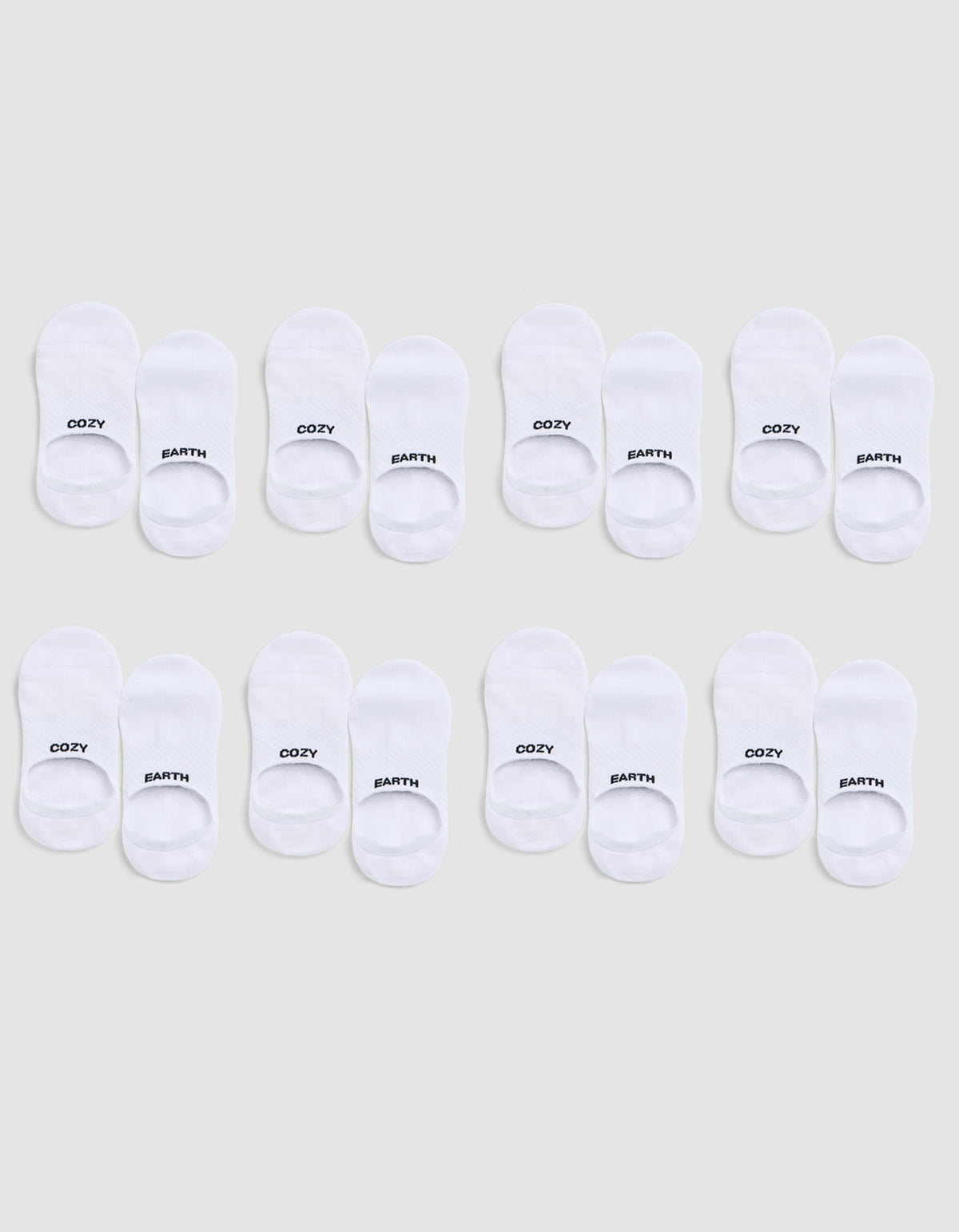 Eight pairs of white Essential No-Show Socks by Cozy Earth are arranged in three rows on a light gray background; each pair is labeled “COZY” on one sock and “EARTH” on the other. 