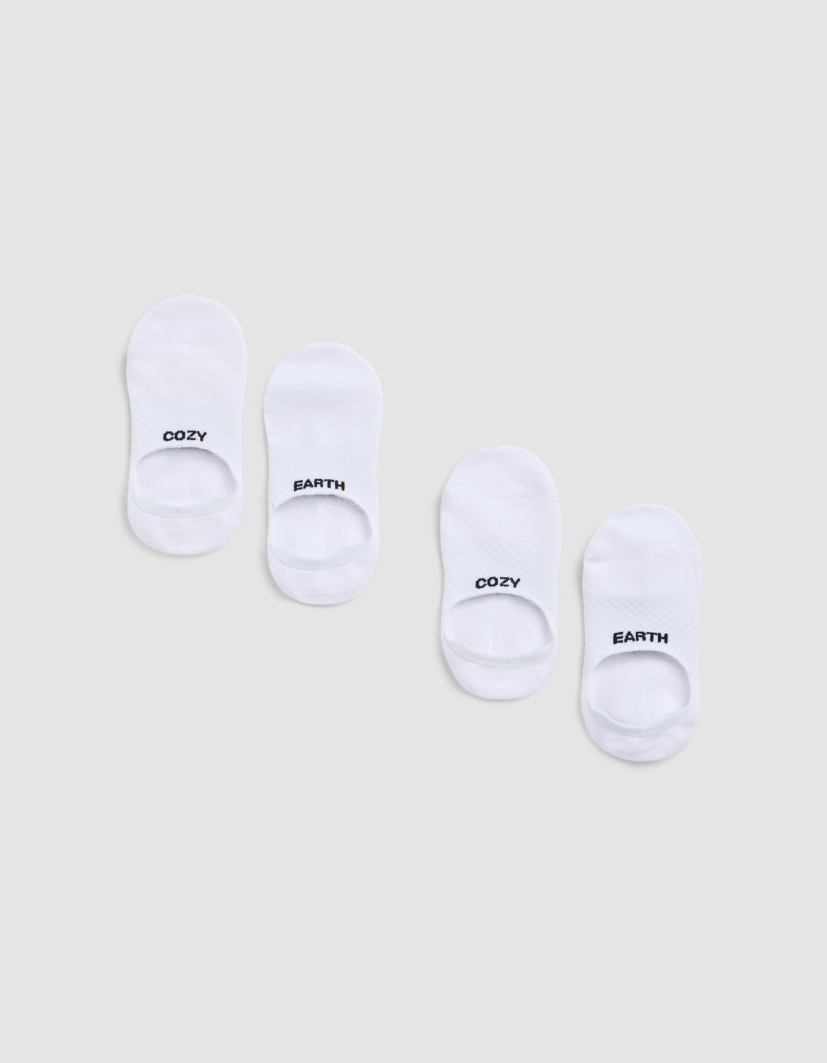 Two pairs of Cozy Earth Essential No-Show Socks are displayed on a light gray background. Each pair features "COZY" on one sock and "EARTH" on the other, both printed in black near the toes. 