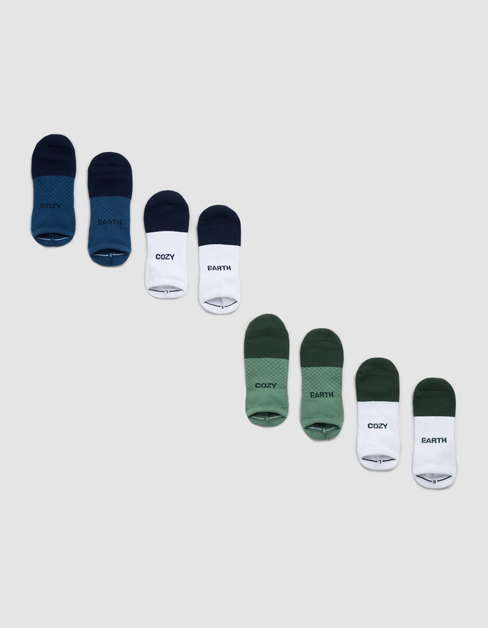 The Cozy Earth Essential Ankle Sock 4-Pack includes green, blue, and white socks, some featuring "COZY" or "EARTH" text, arranged diagonally on a light gray background. |Color:Spruce/Eclipse