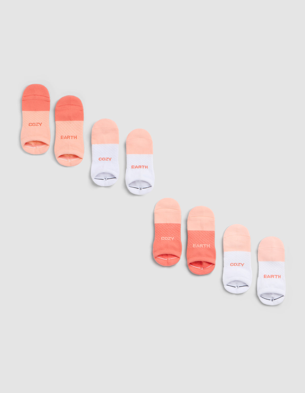 The Cozy Earth Essential Ankle Sock 4-Pack features socks in coral, peach, and white, each with "COZY" or "EARTH" near the toes, shown diagonally on a light gray background. |Color:Cantaloupe