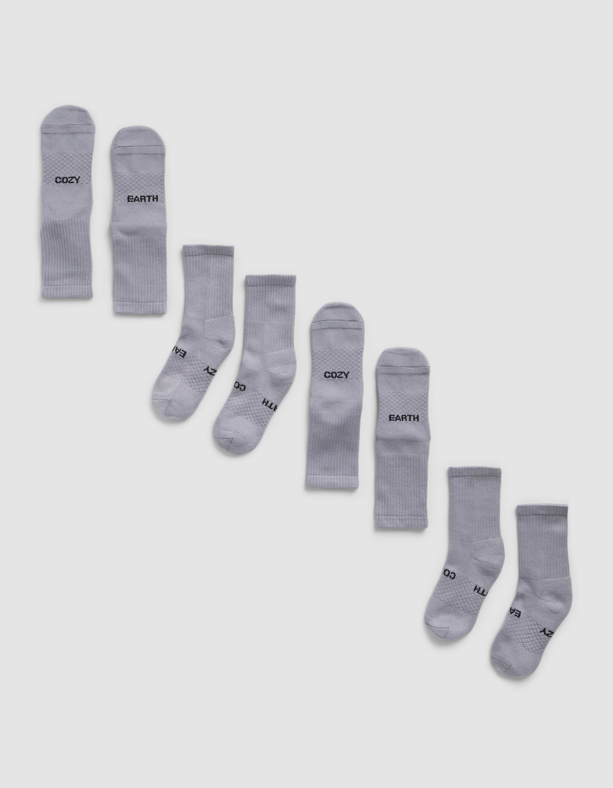 Eight pairs of Cozy Earth Essential Calf Socks, shown side by side in light gray on a white background, display both top and bottom views. Some socks feature black text near the cuffs and toes.