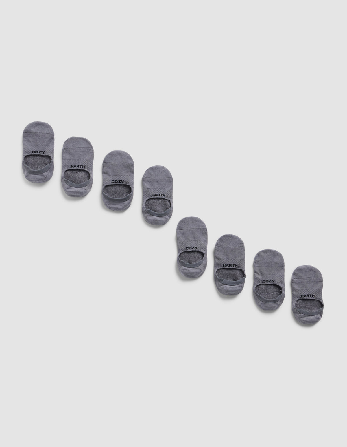 Eight pairs of Cozy Earth Essential No-Show Socks are displayed diagonally on a light gray background, neatly aligned in alternating pairs with black text near the toe.|Color:Stone