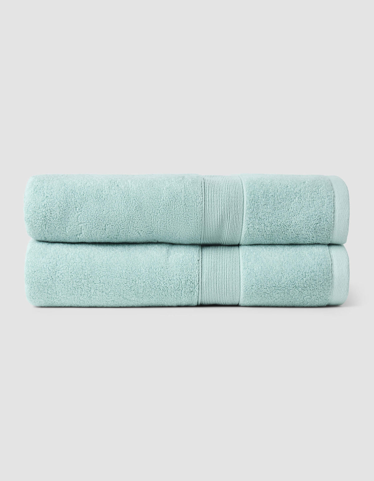 Two Luxe Bath Towels from Cozy Earth, neatly folded and stacked, displayed against a plain light gray background.