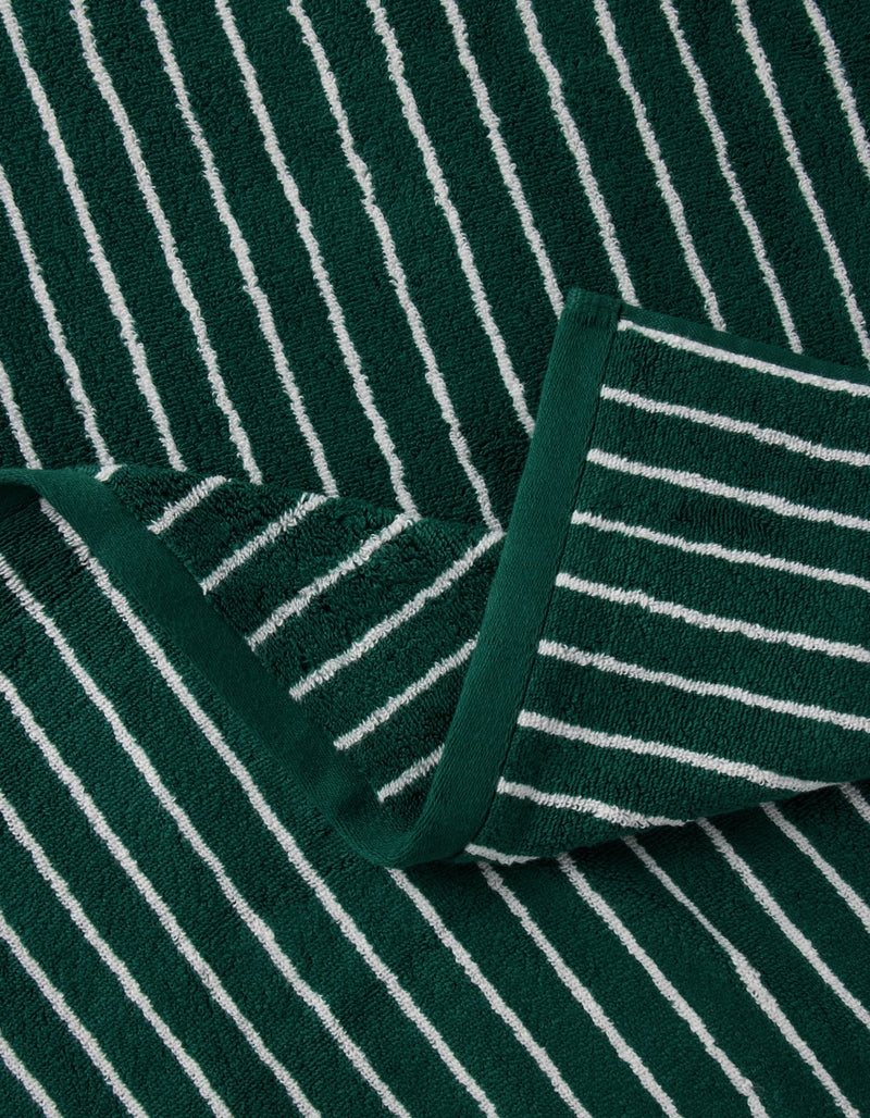 A Luxe Washcloth by Cozy Earth in green with white vertical stripes is neatly folded, highlighting its textured, striped fabric.