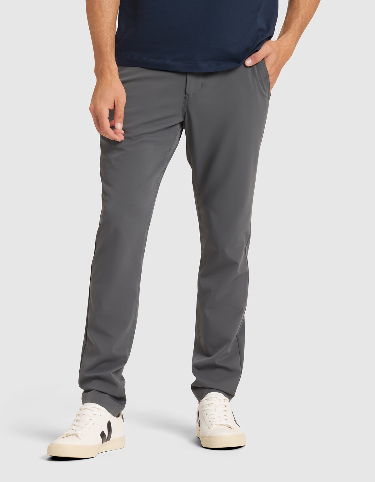 A person wears Cozy Earth Men's Everywhere Pant with white sneakers featuring black details, against a plain light background. Only the lower half is visible, with one hand in a pocket. 