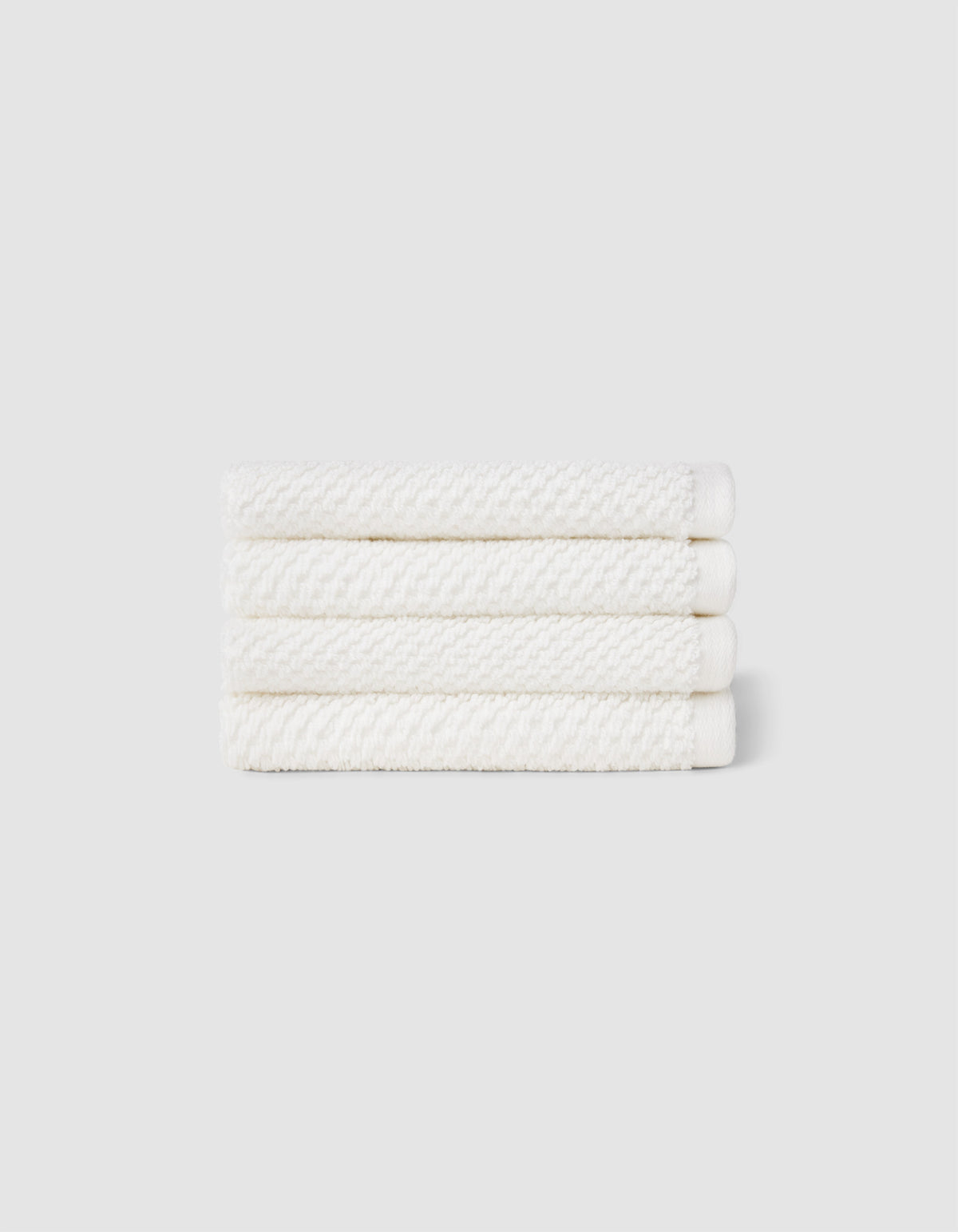 Four neatly folded Nantucket Washcloths by Cozy Earth, stacked horizontally against a plain light gray background.