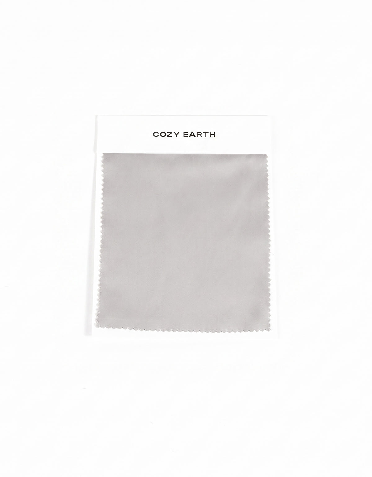 A gray Soft-Wash Cotton Sheet swatch with zigzag edges is attached to a white card labeled "Cozy Earth" at the top, displayed on a plain white background.