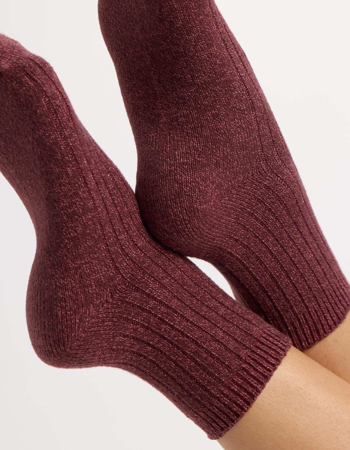 A pair of feet wear Cozy Earth's Plush Lounge Quarter Socks in burgundy, featuring a cozy ribbed knit and textured pattern, shown against a plain light background.