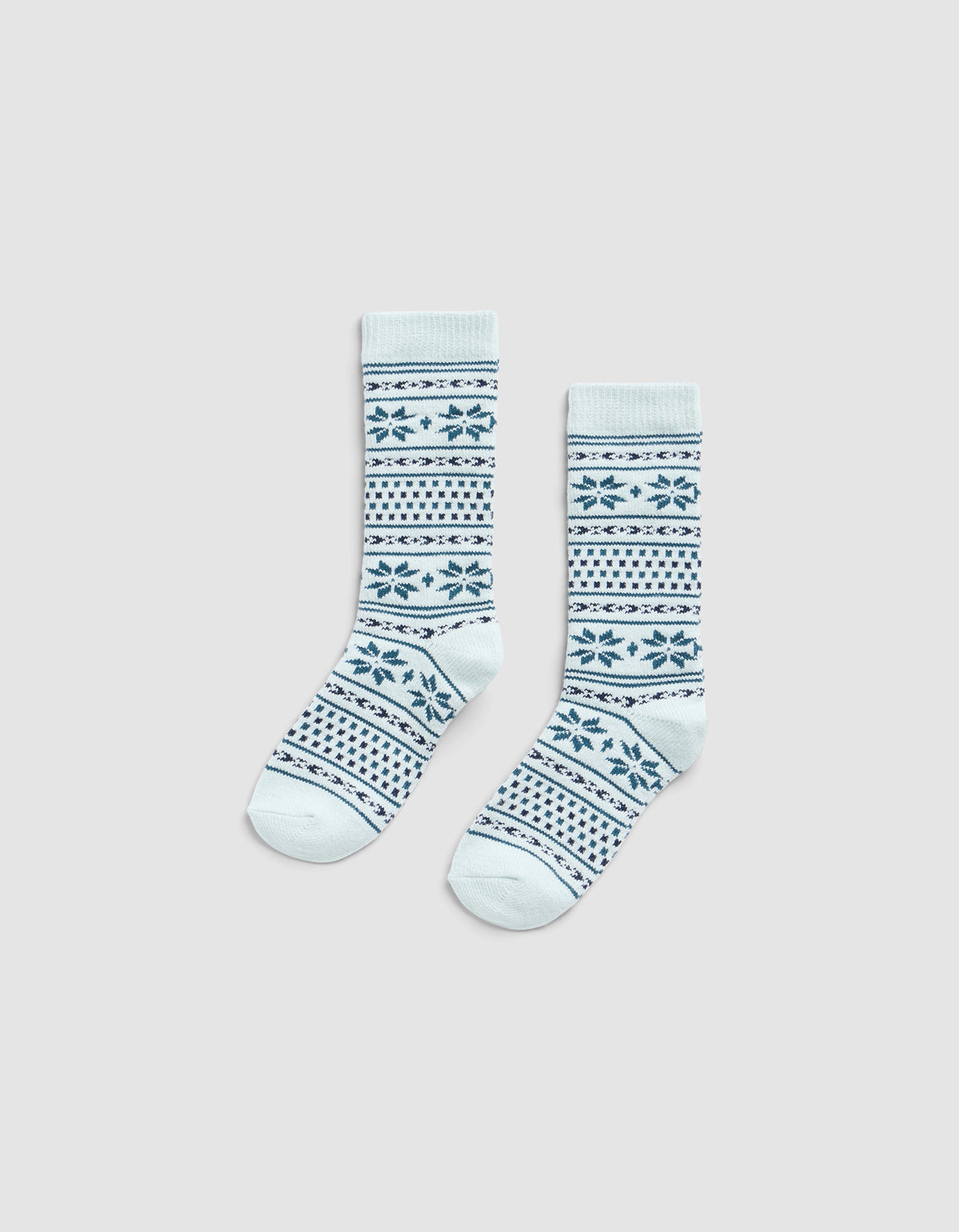 The Cozy Earth Snowflake Plush Lounge Sock features light blue fabric with dark blue geometric and snowflake stripes, shown on a plain light gray background.|Color:Mist