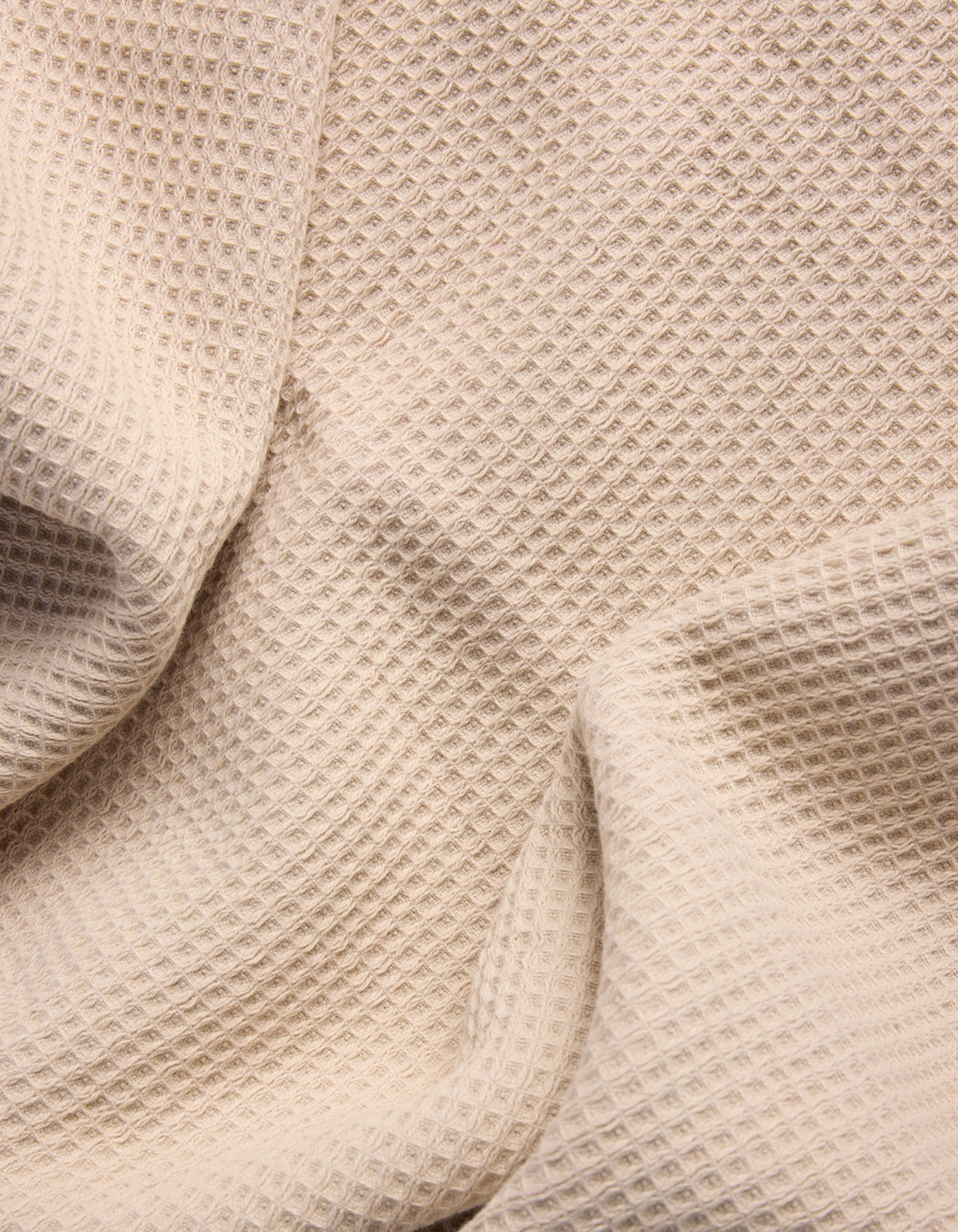 The Cozy Earth Waffle Bath Towel Set features beige waffle-textured fabric with a grid-like pattern, shown draped in soft folds. |Color:Birch